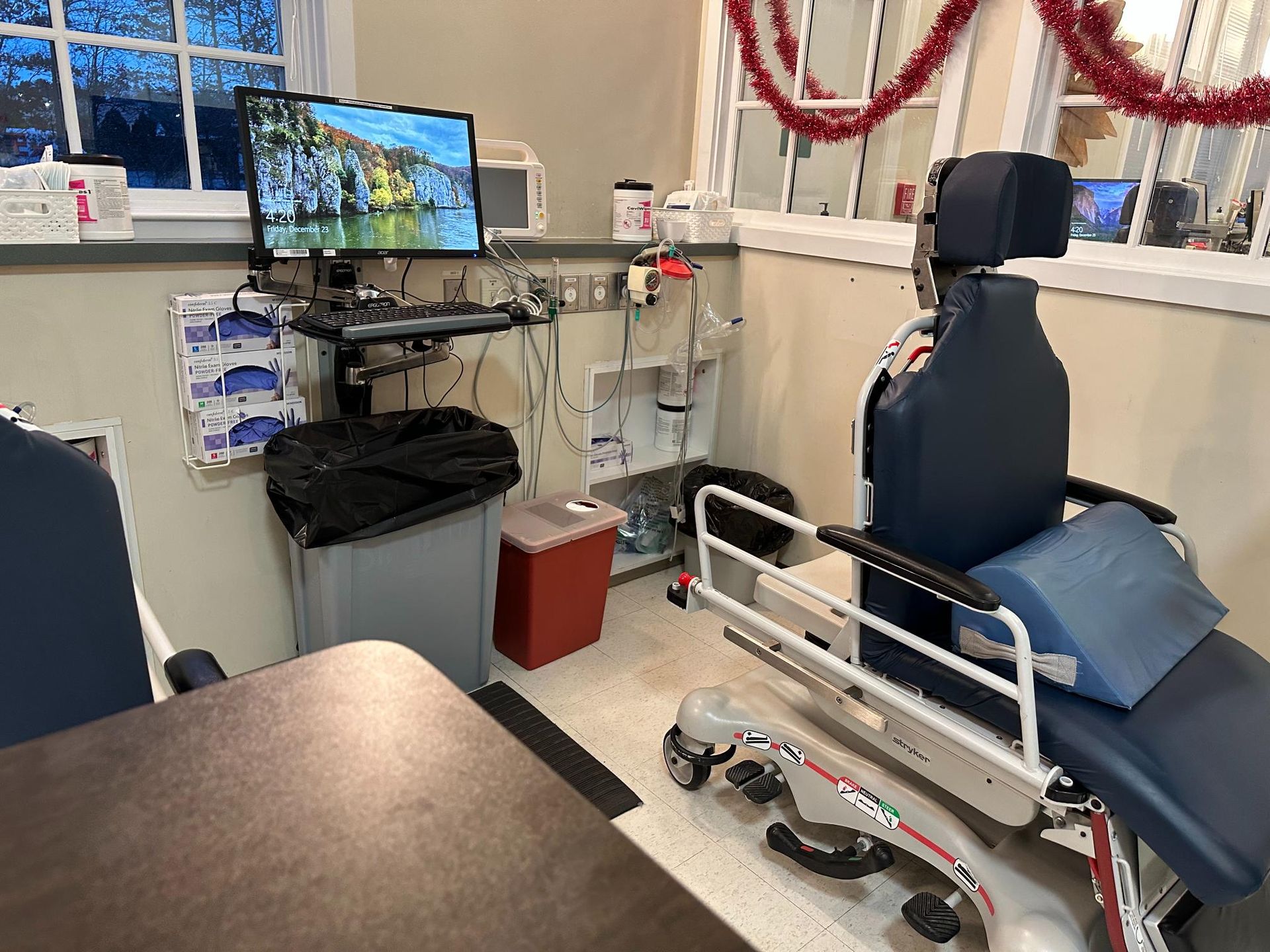 A hospital room with a chair and a computer on a desk.