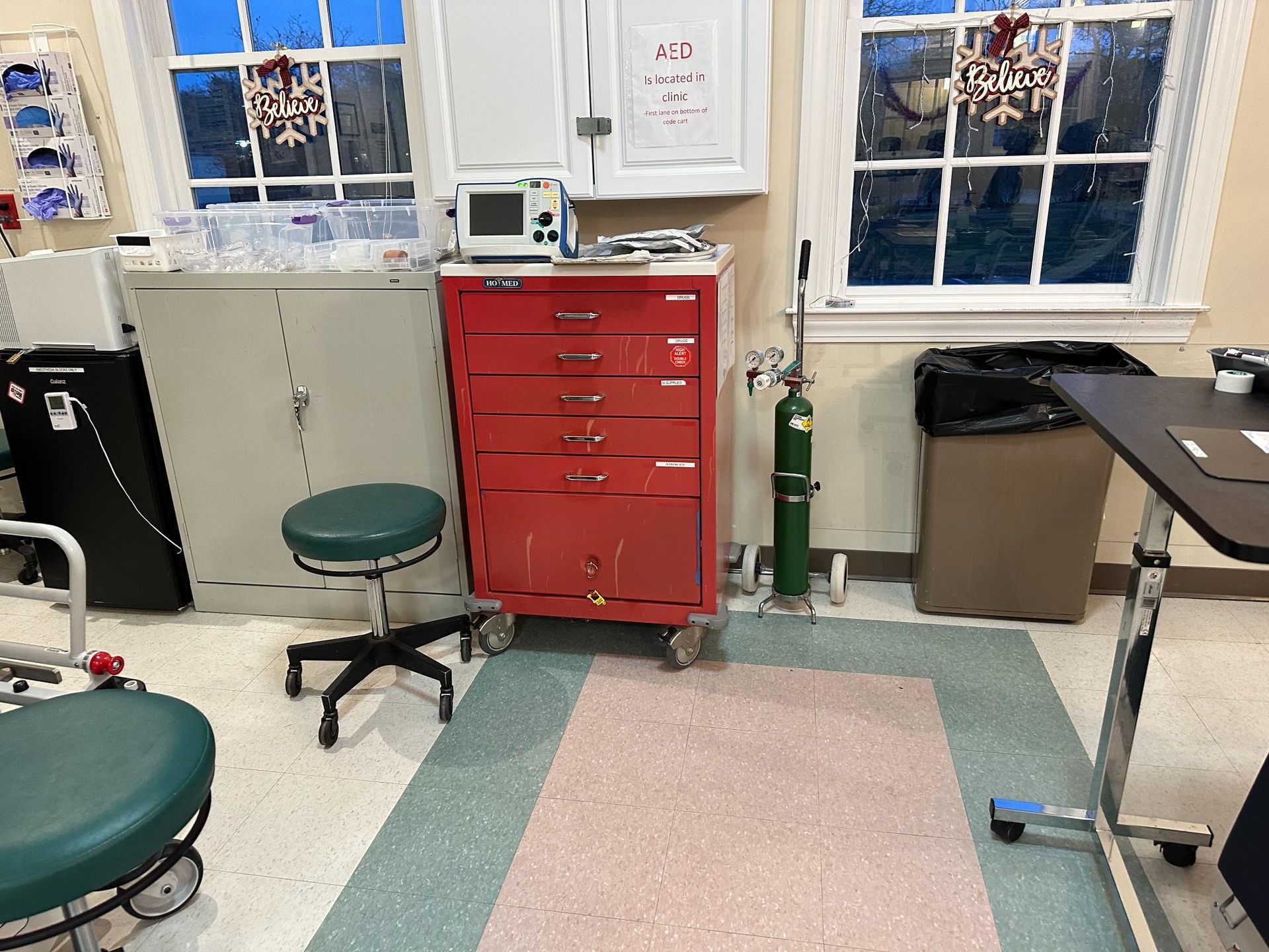 A dental office with a green chair and a red cart