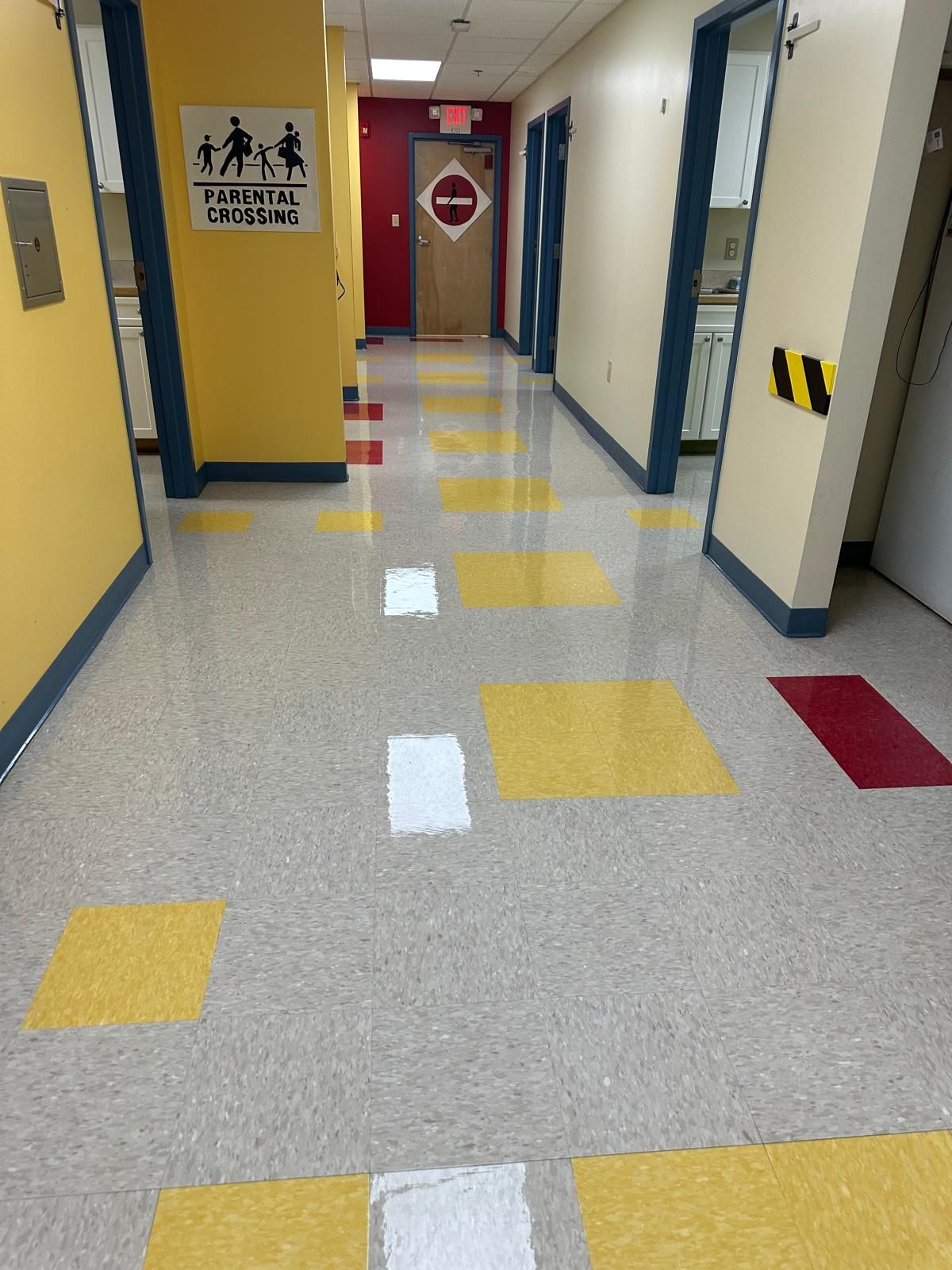 A hallway with yellow and white tiles and a sign on the wall
