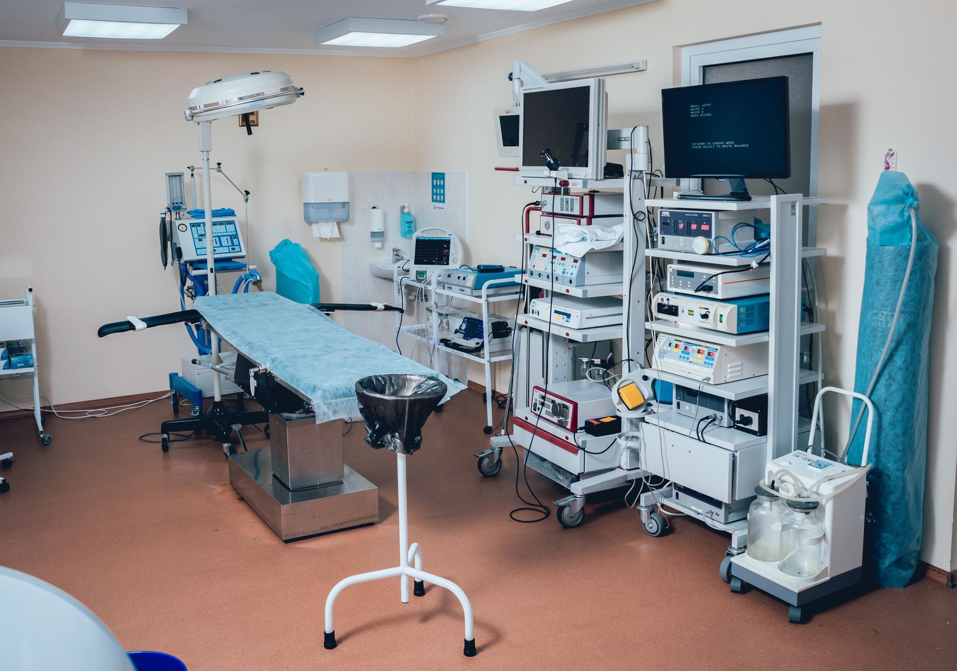 An empty operating room with a bed , monitors , and other medical equipment.