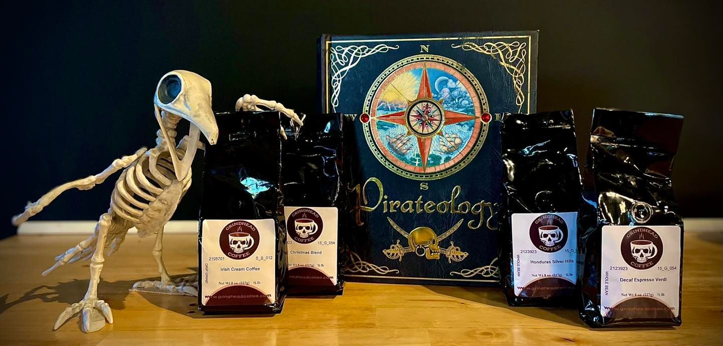 A skeleton bird figure stands beside four coffee bags in front of a 