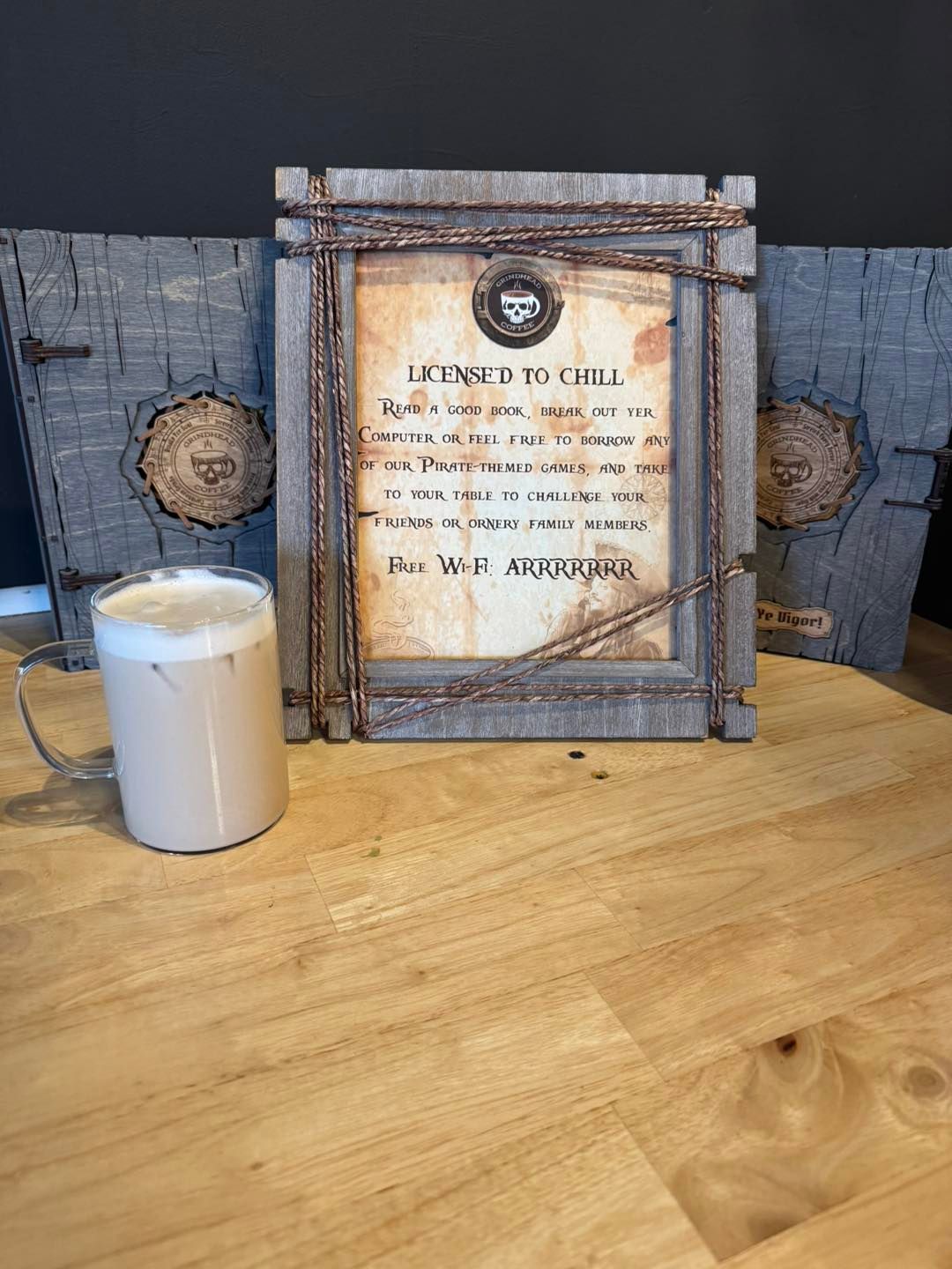 A glass of iced coffee stands before a framed 
