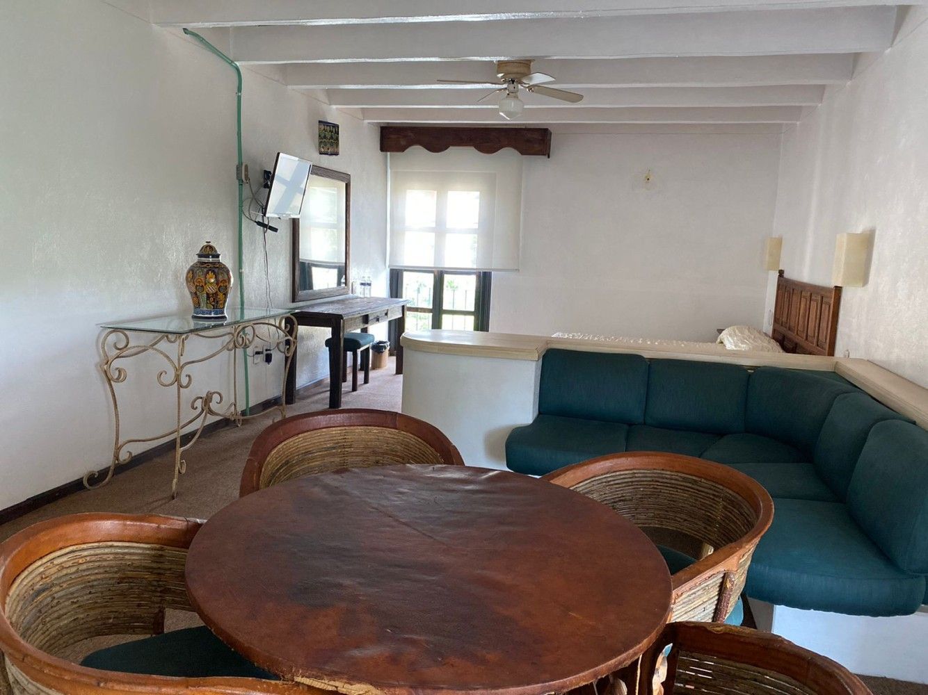 Luminoso salón-comedor con sofá modular de color verde azulado, mesa redonda de madera y paredes blancas.