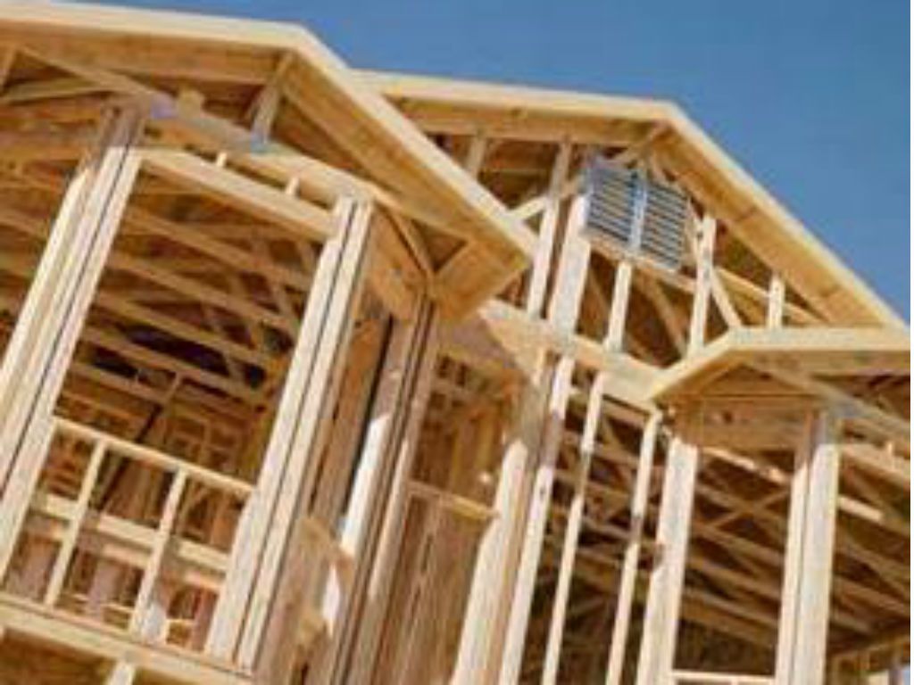 Wooden house under construction; frame visible, blue sky in background.
