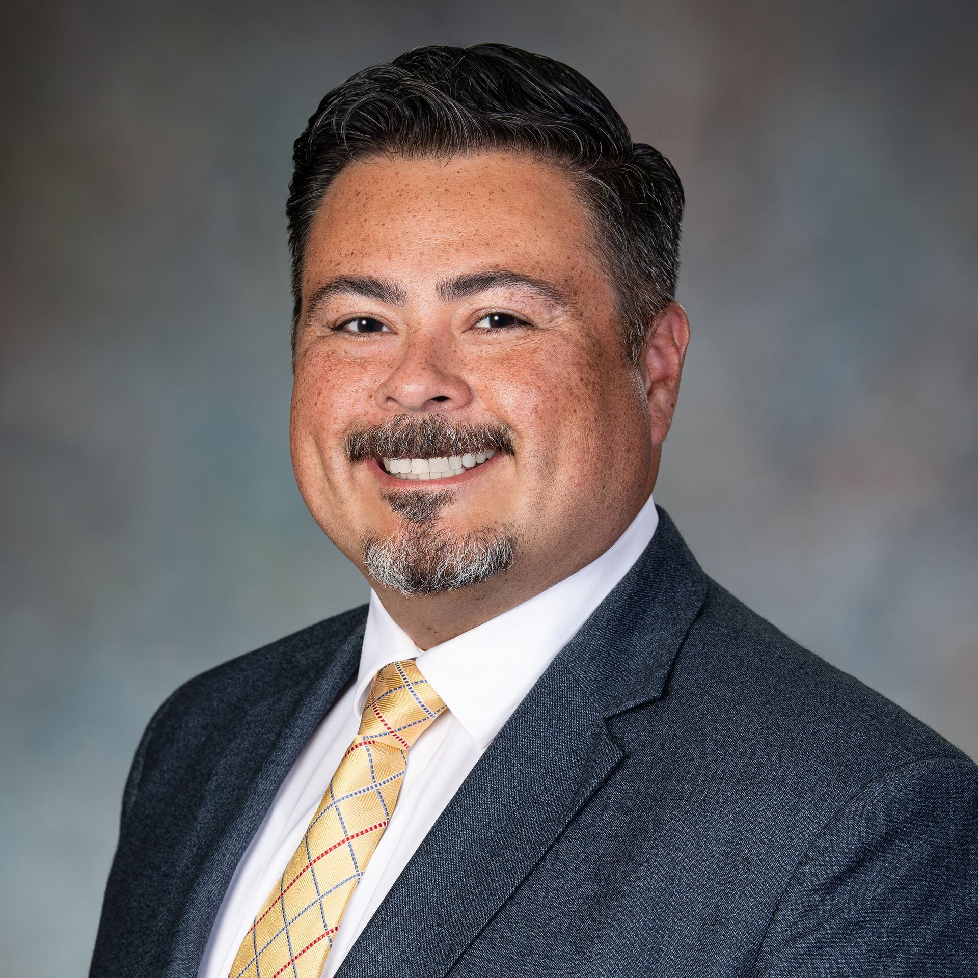 A smiling man in a suit and tie; headshot.