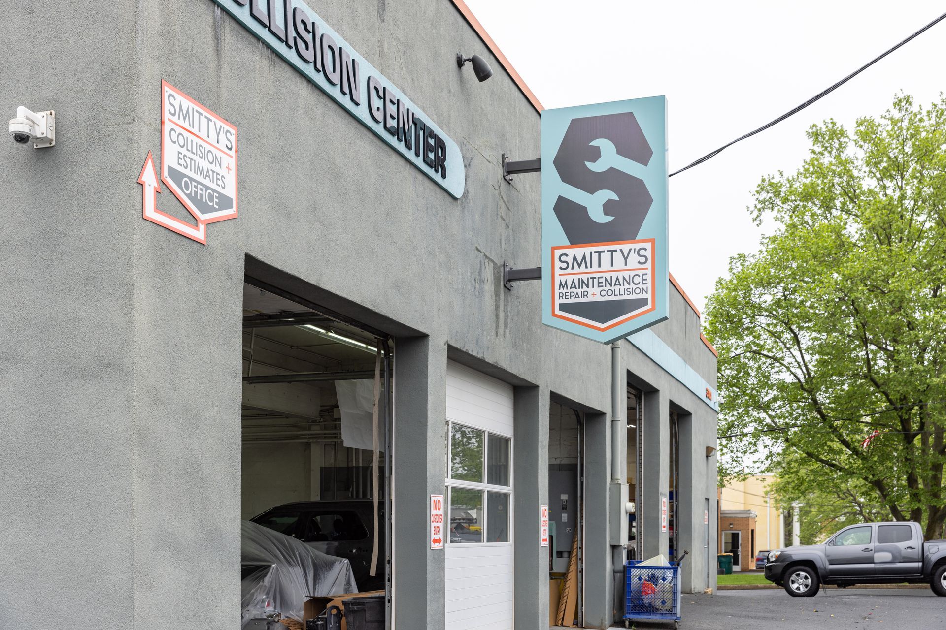 Switty's Collision Center, gray building with open garage bays; sign with stylized