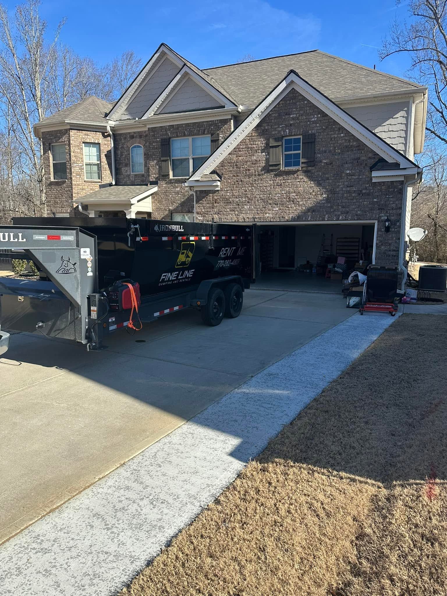 Brick suburban house with a moving truck parked in the driveway and workers unloading items at the garage