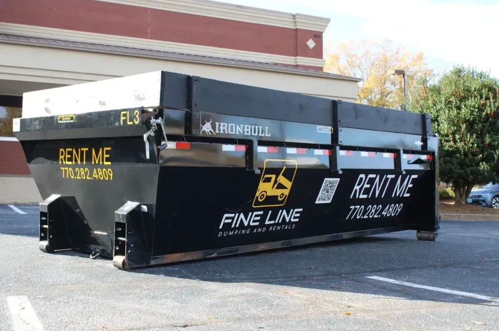 Black dumpster trailer in a parking lot with “Rent Me” and “Fine Line” lettering