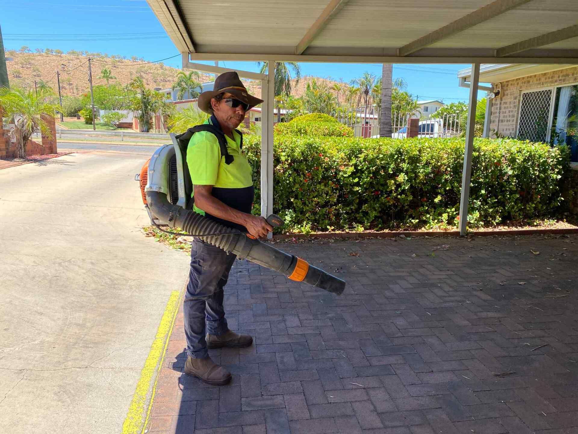 Man Using a Backpack Leaf Blower on a Brick Paved Area — Darrell's Mowing Services in Sunset, QLD