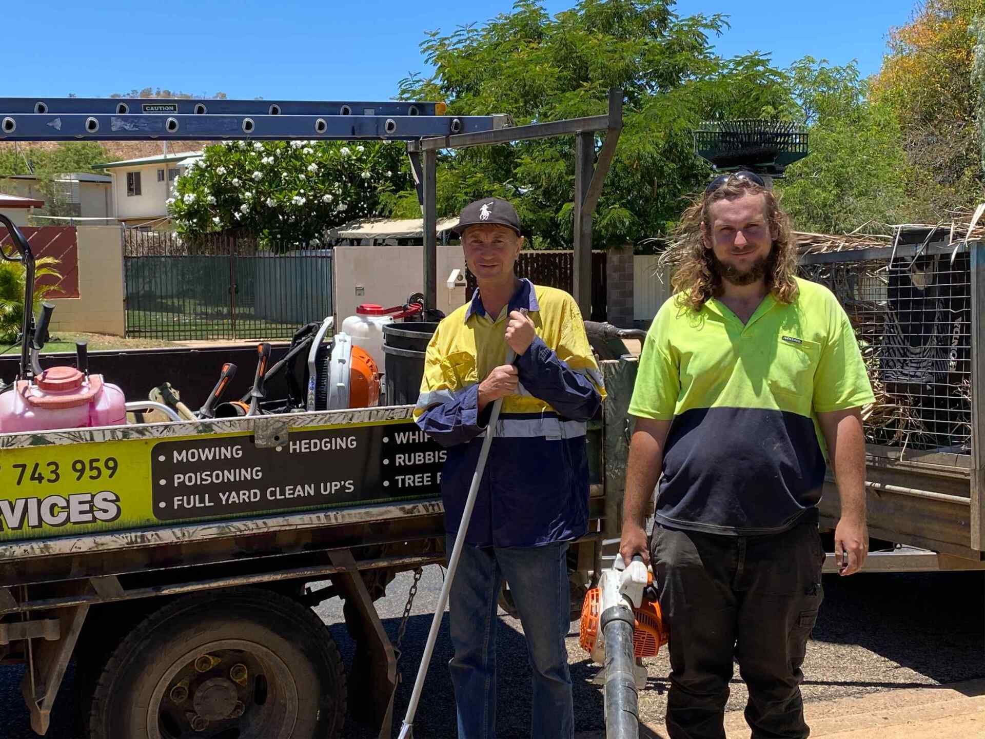 Two Men in Work Clothes Stand Next to a Truck With