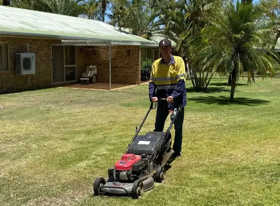 Person Mowing a Green Lawn with A Push Mower — Darrell's Mowing Services in Cloncurry, QLD