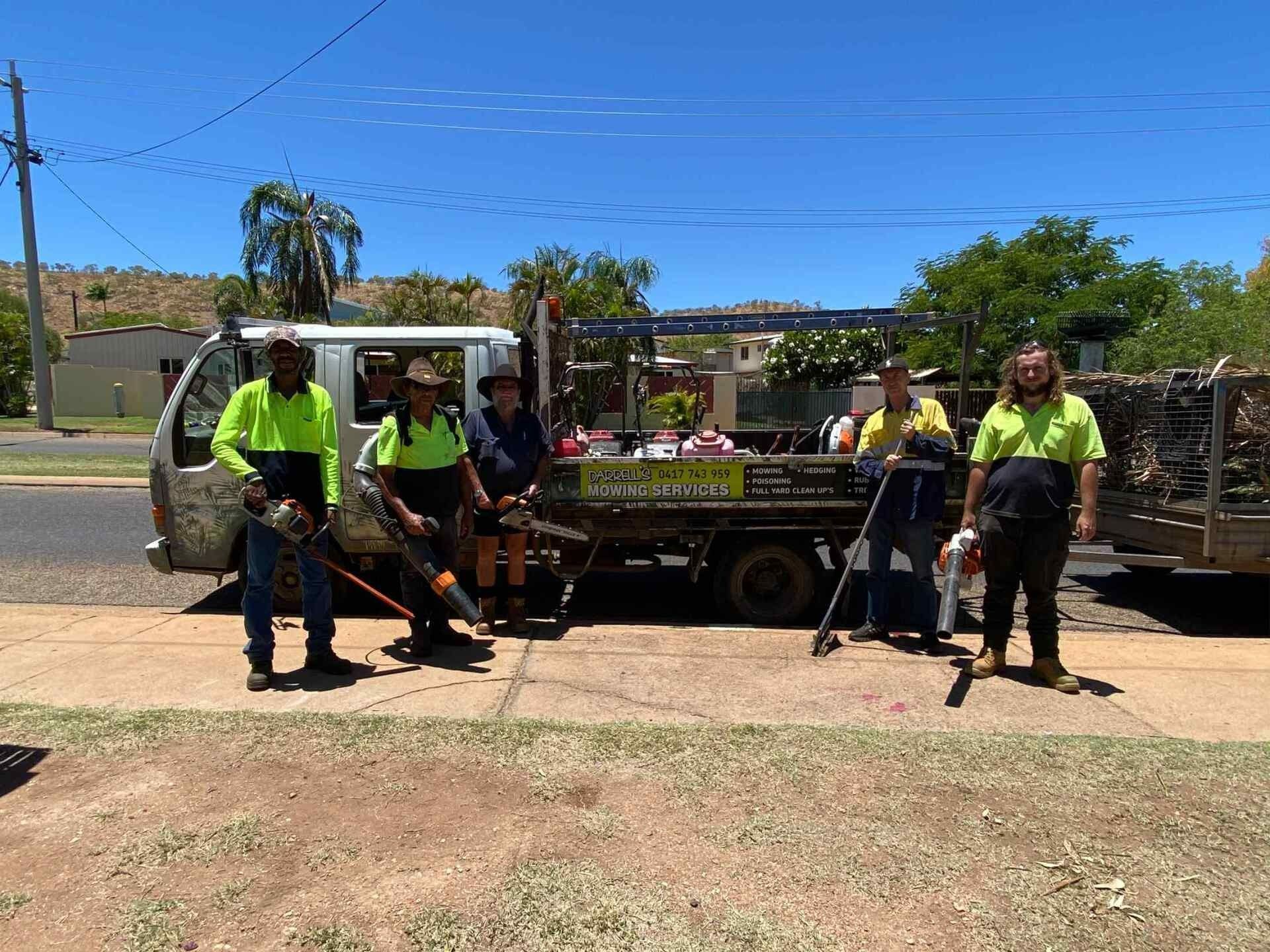Workers in Safety Vests With Tools Stand Near a Truck — Darrell's Mowing Services in Sunset, QLD