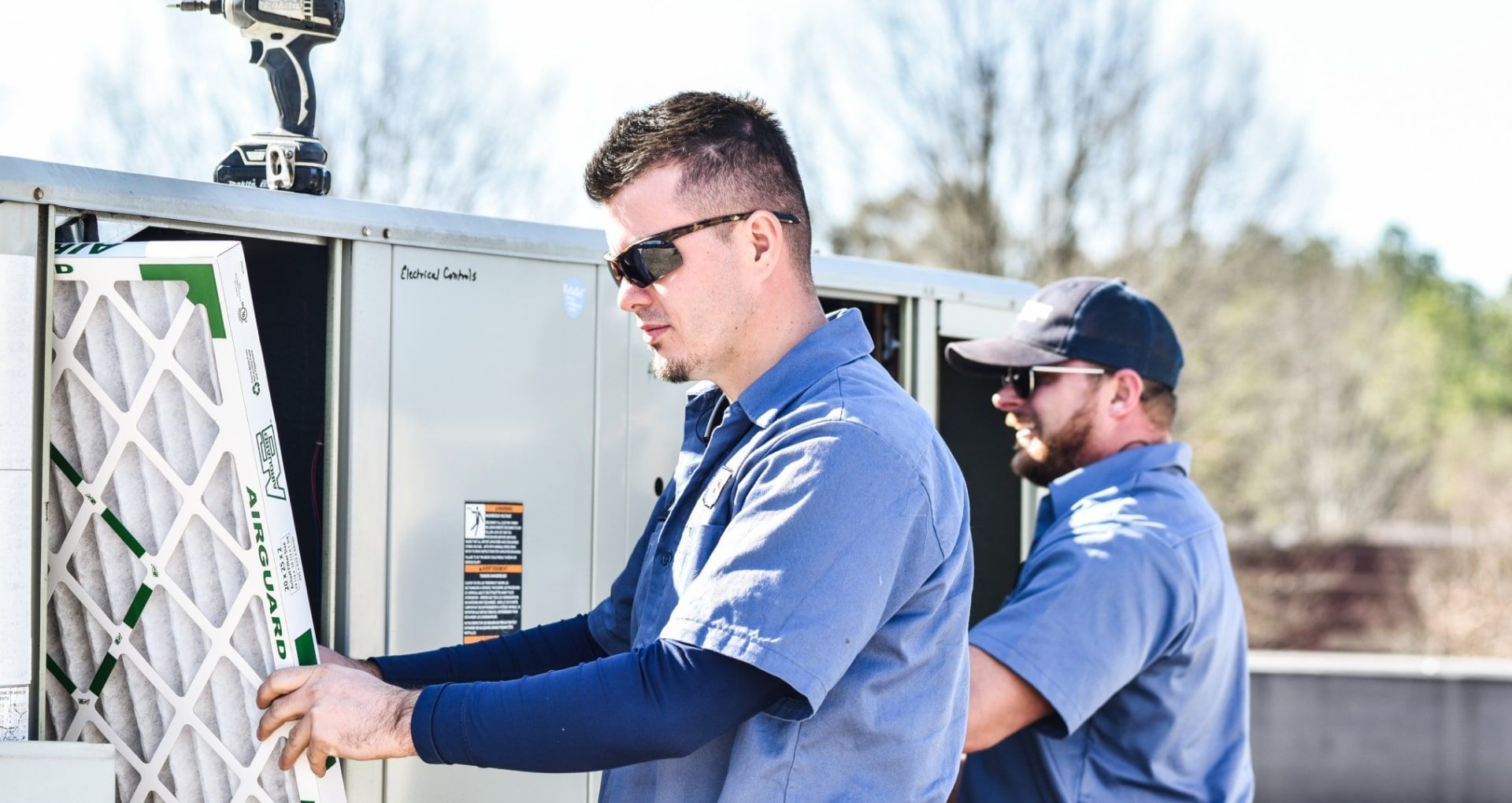 Two men are working on an air conditioning system.