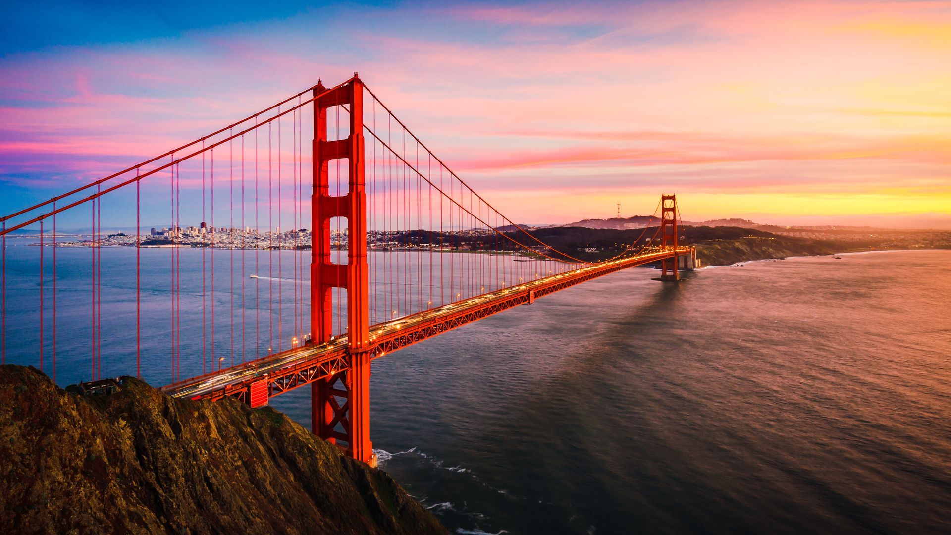 Golden Gate Bridge spanning the blue waters of San Francisco Bay, with a clear sky in the background.