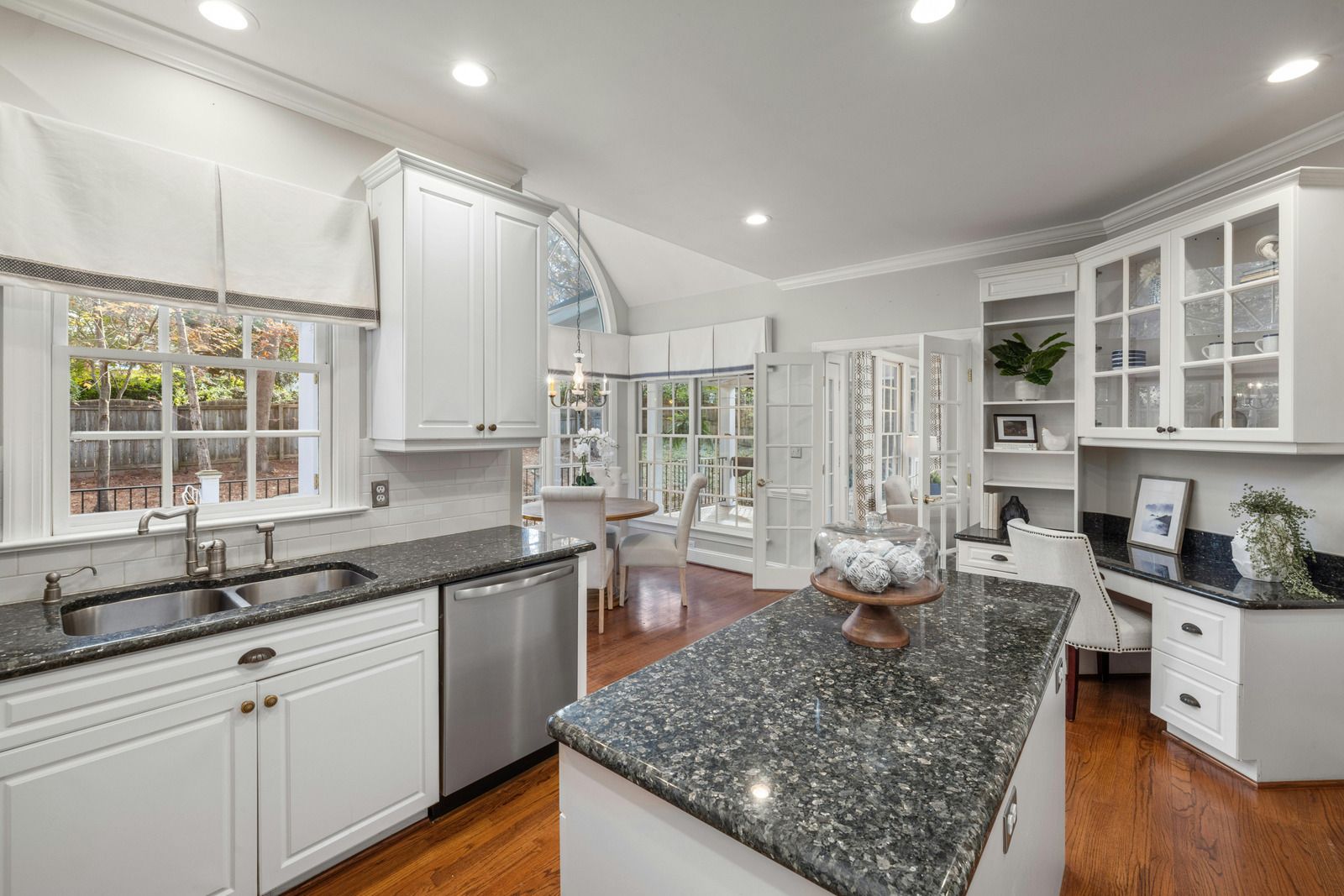 Bright modern kitchen with white cabinets, granite island, and stainless steel appliances