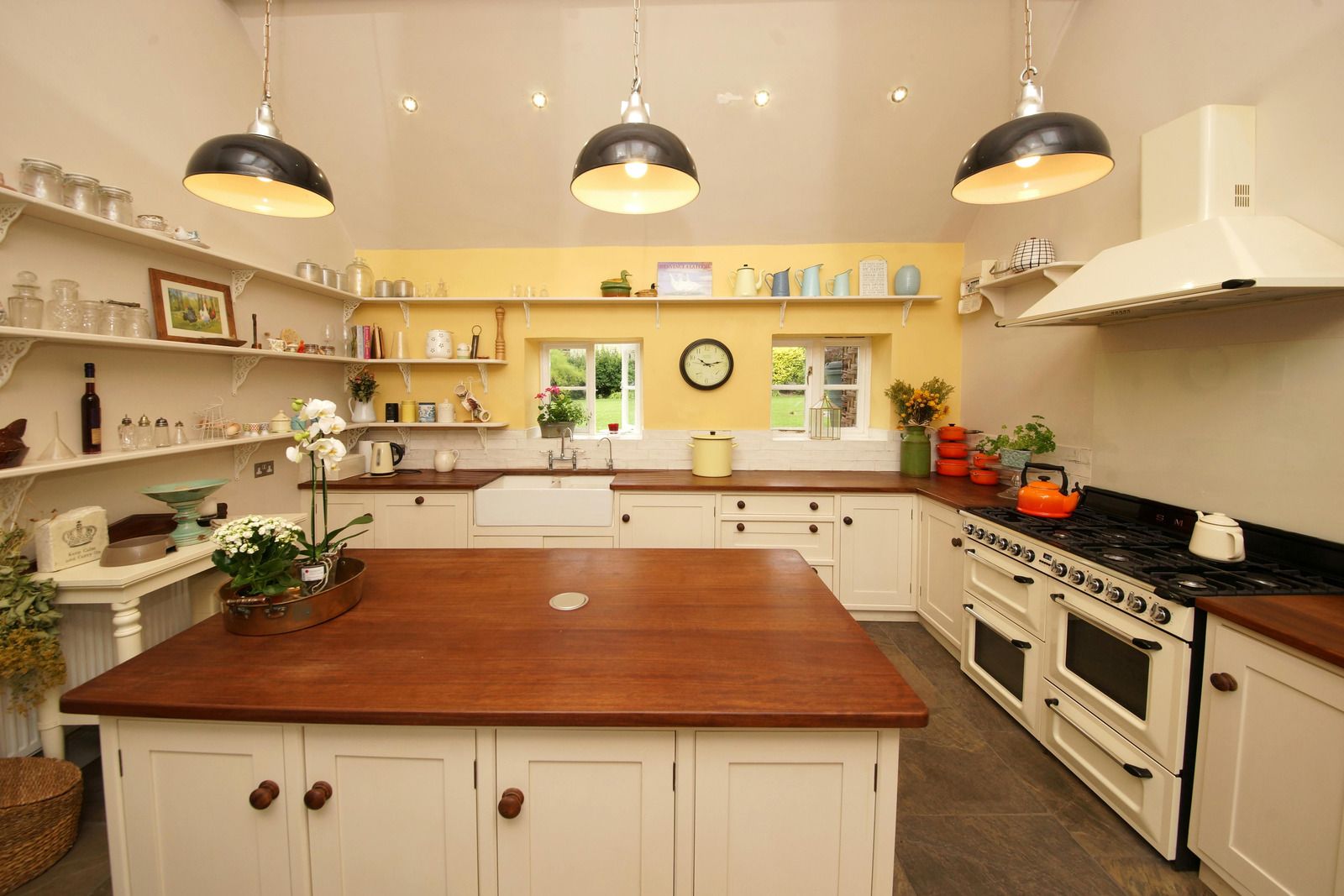 Bright, cozy kitchen with white cabinets, wood island, black countertops, and hanging pendant lights