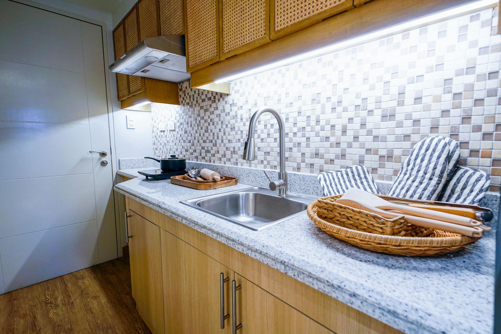 Modern kitchen counter with stainless sink, granite countertop, wicker bread basket, and striped dish towel.
