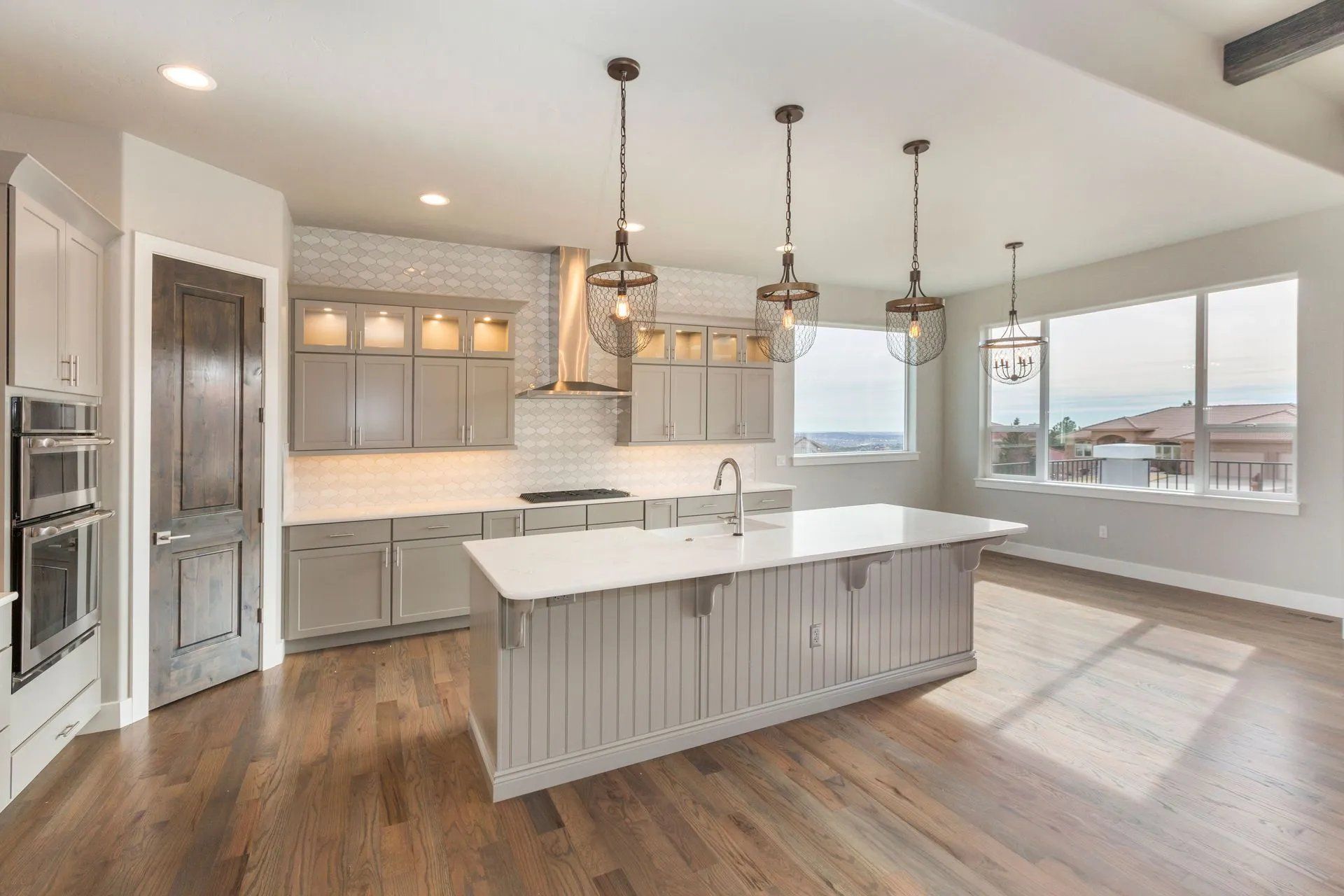 Bright modern kitchen with white cabinets, large island, stainless appliances, and hardwood floors