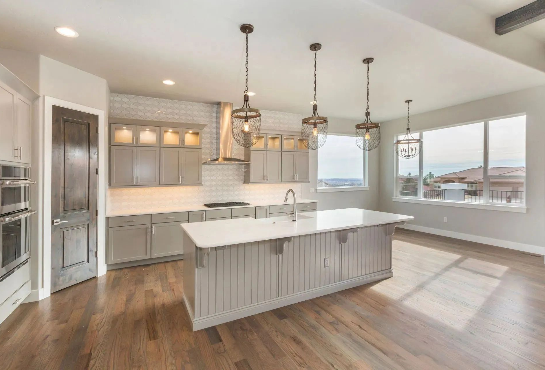 Bright modern kitchen with white cabinets, large island, pendant lights, and hardwood floors