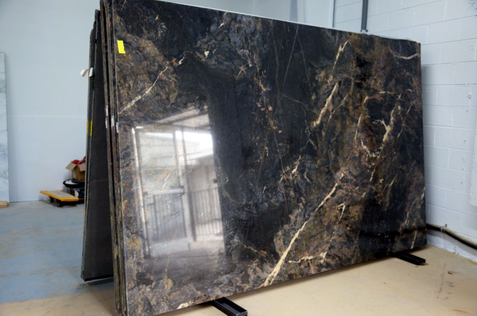 Large glossy black marble slab leaning upright against a wall in a workshop.