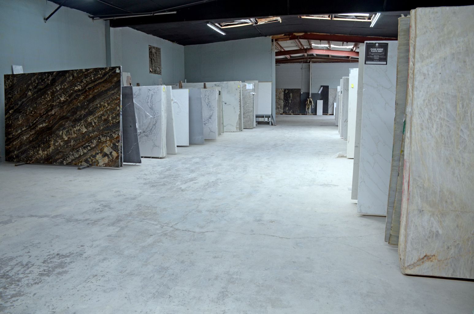 Indoor warehouse-like room with large stone slabs or panels standing upright on a white floor.