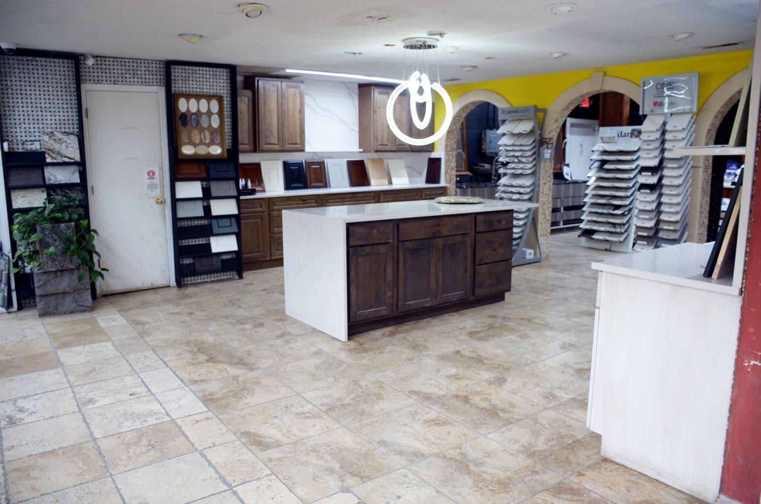 Empty room with tiled floor, central island counter, stacked chairs, and yellow walls