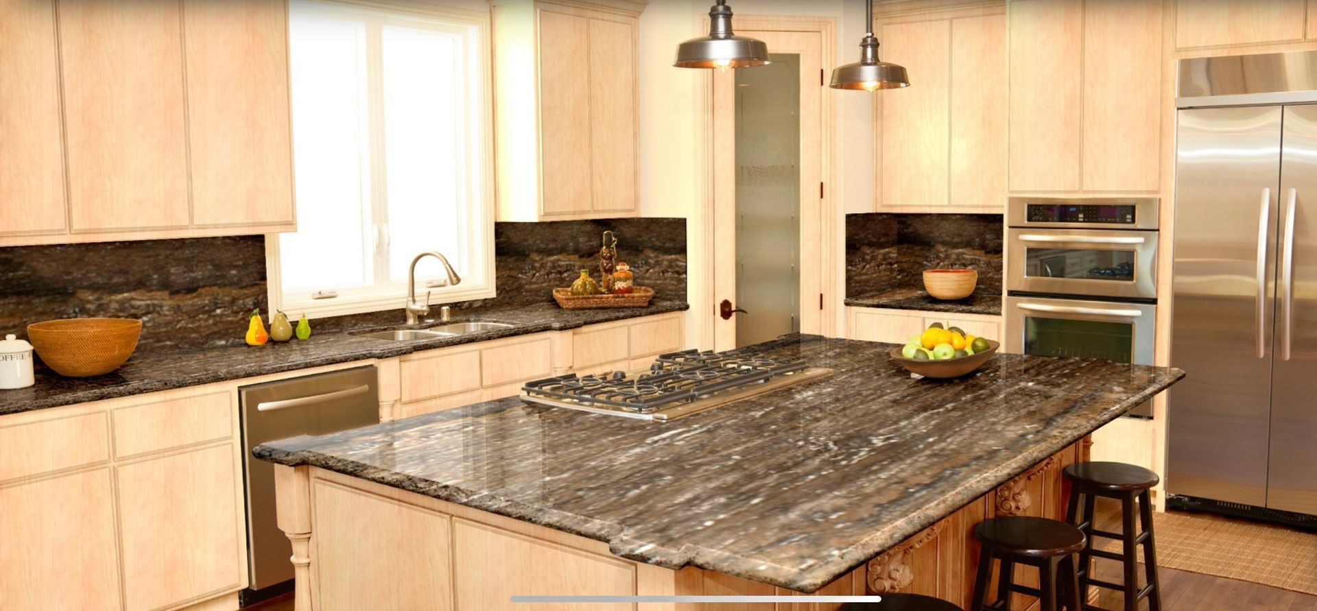 Modern kitchen with a large granite island, pendant lights, and stainless steel appliances