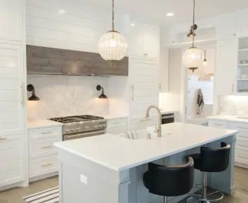 Bright white modern kitchen with island, pendant lights, and stainless steel stove