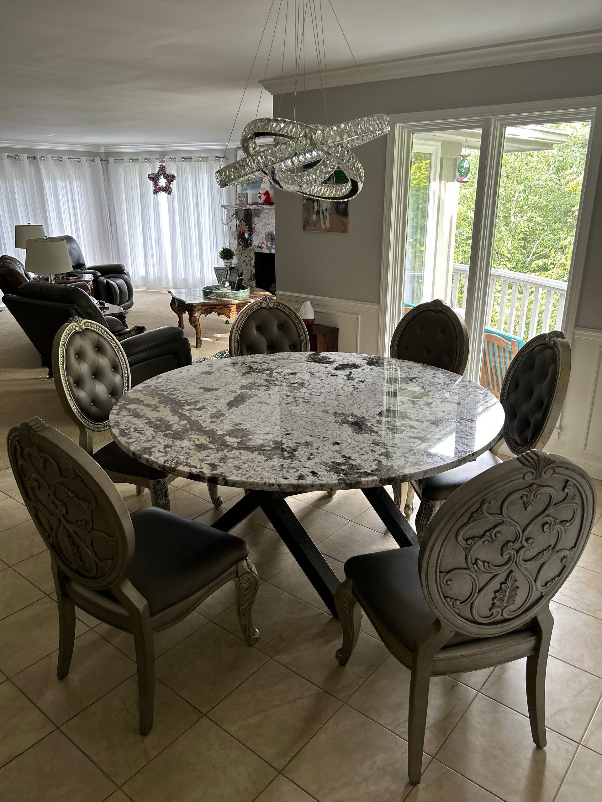 Dining room with round table and upholstered chairs beside a bright sliding glass door.