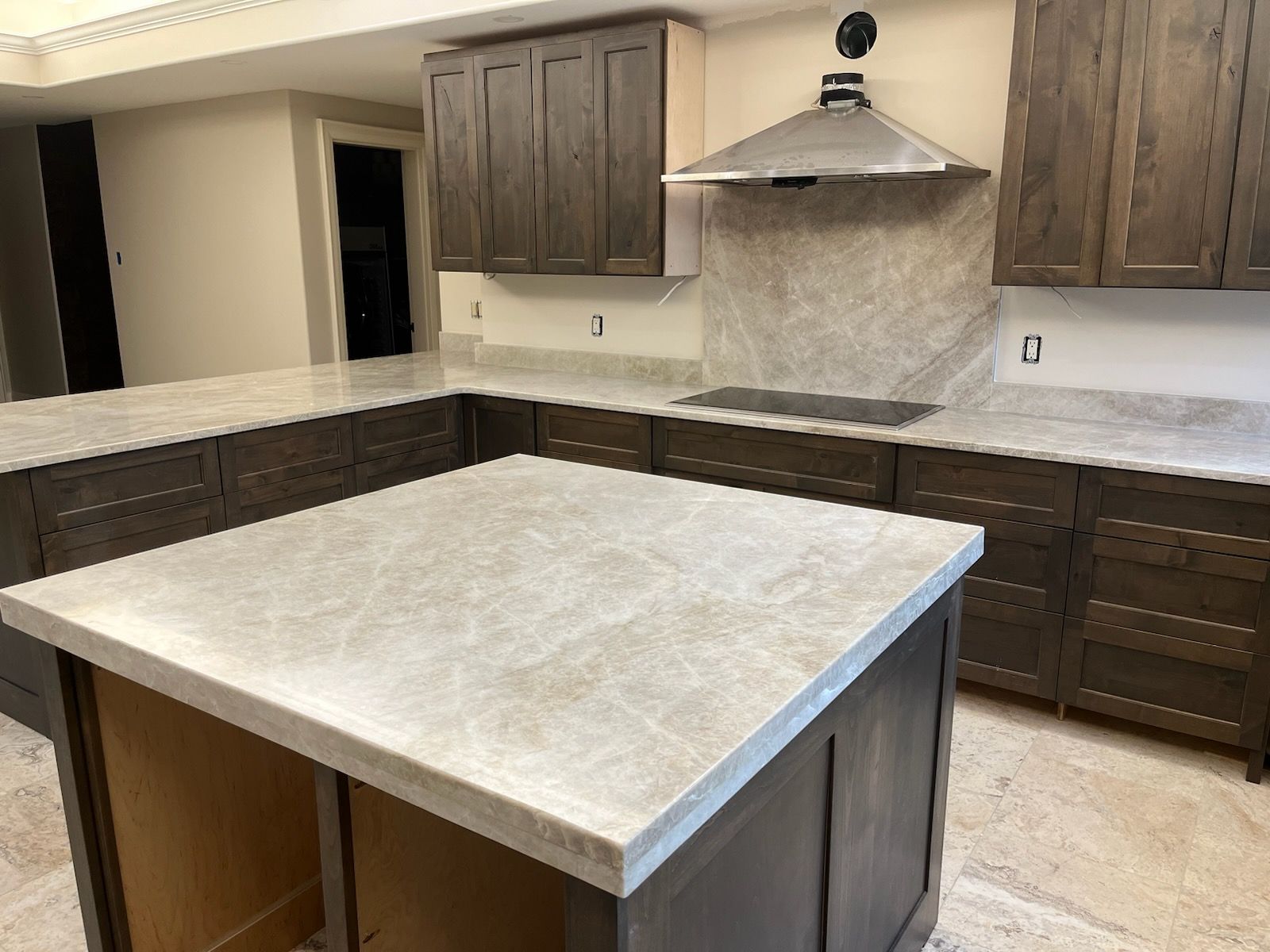 Modern kitchen with dark wood cabinets and a light stone island countertop.