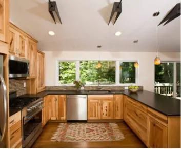 Bright modern kitchen with wood cabinets, dark countertops, stainless appliances, and large windows