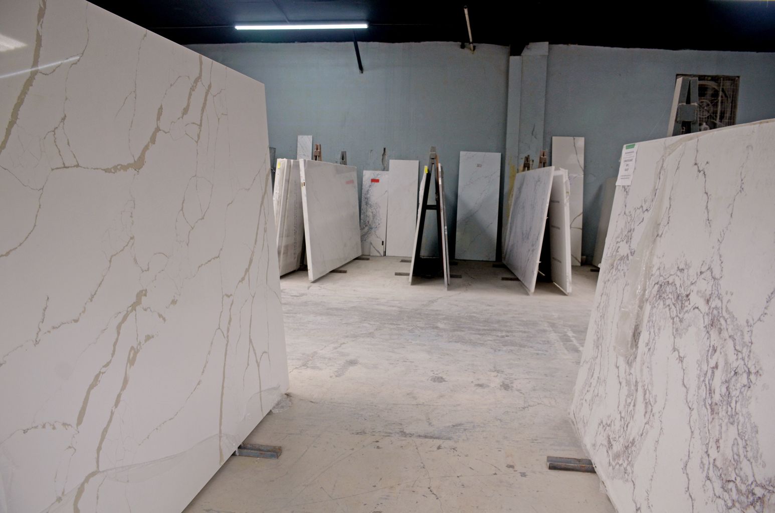 Large marble slabs displayed in a warehouse with a dusty floor and gray walls