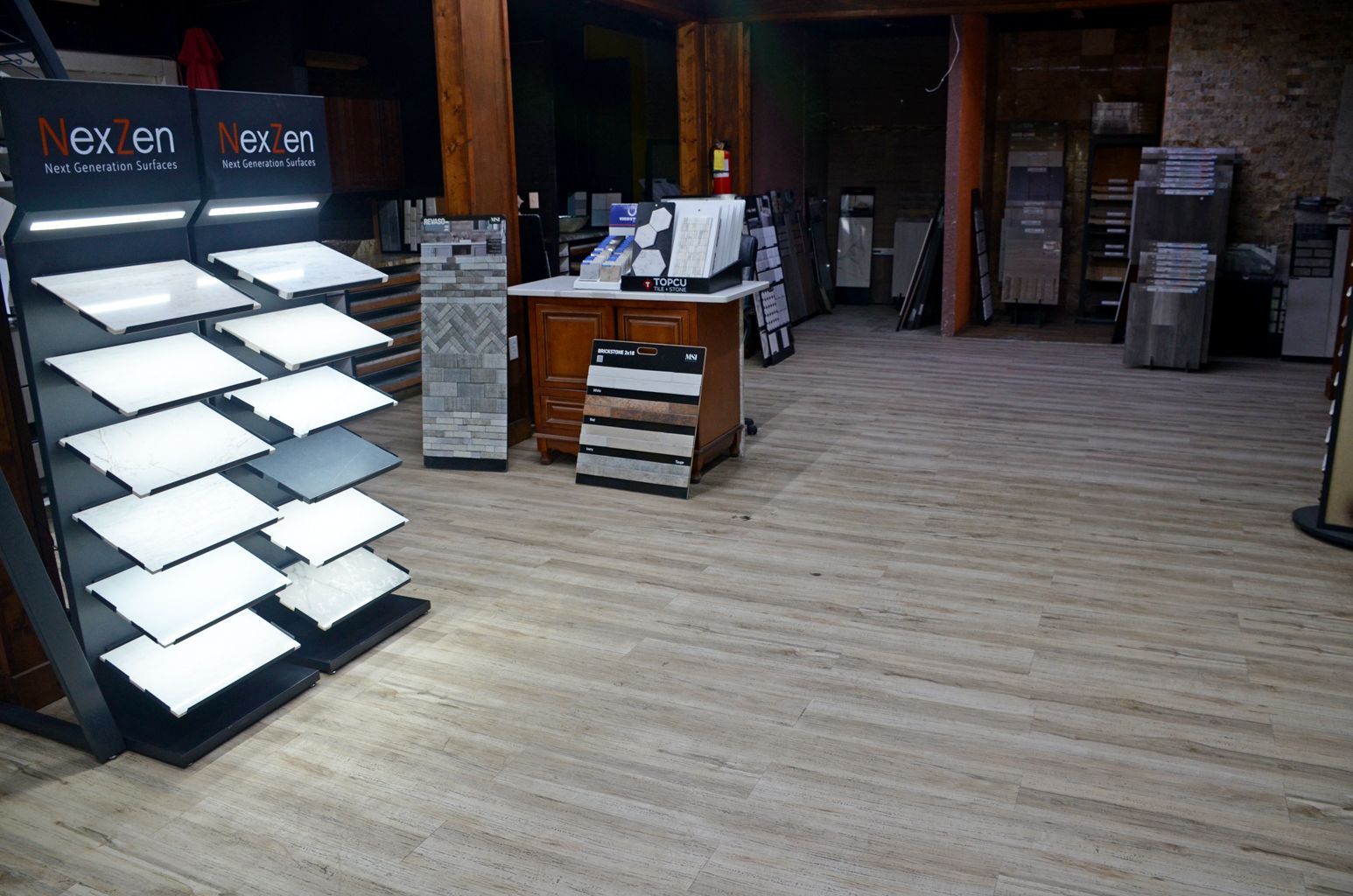 Empty retail showroom with display shelves, wooden floor, and tables in the background