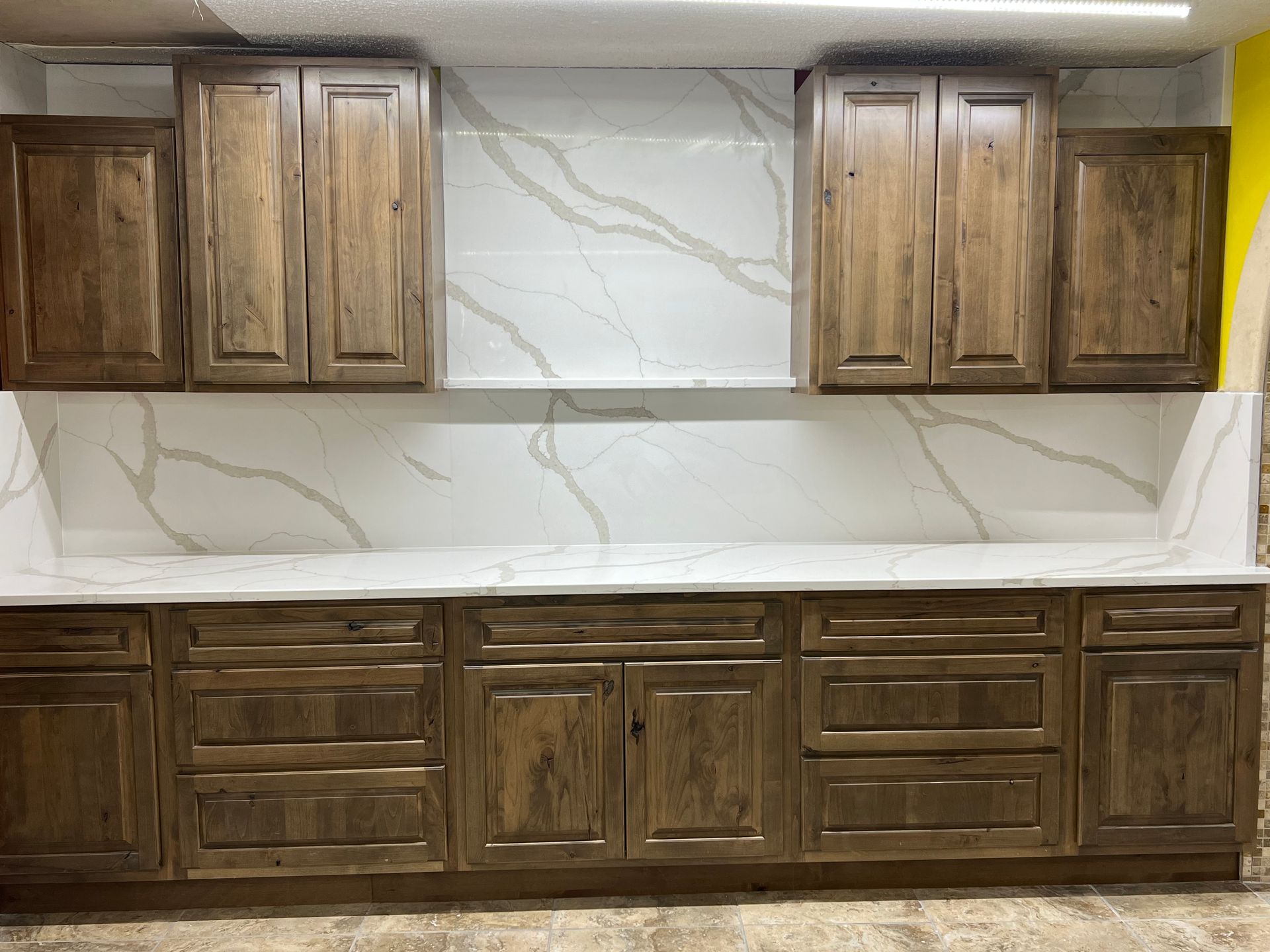 Built-in wooden cabinets with white marble-look backsplash and countertop in a kitchen or laundry area