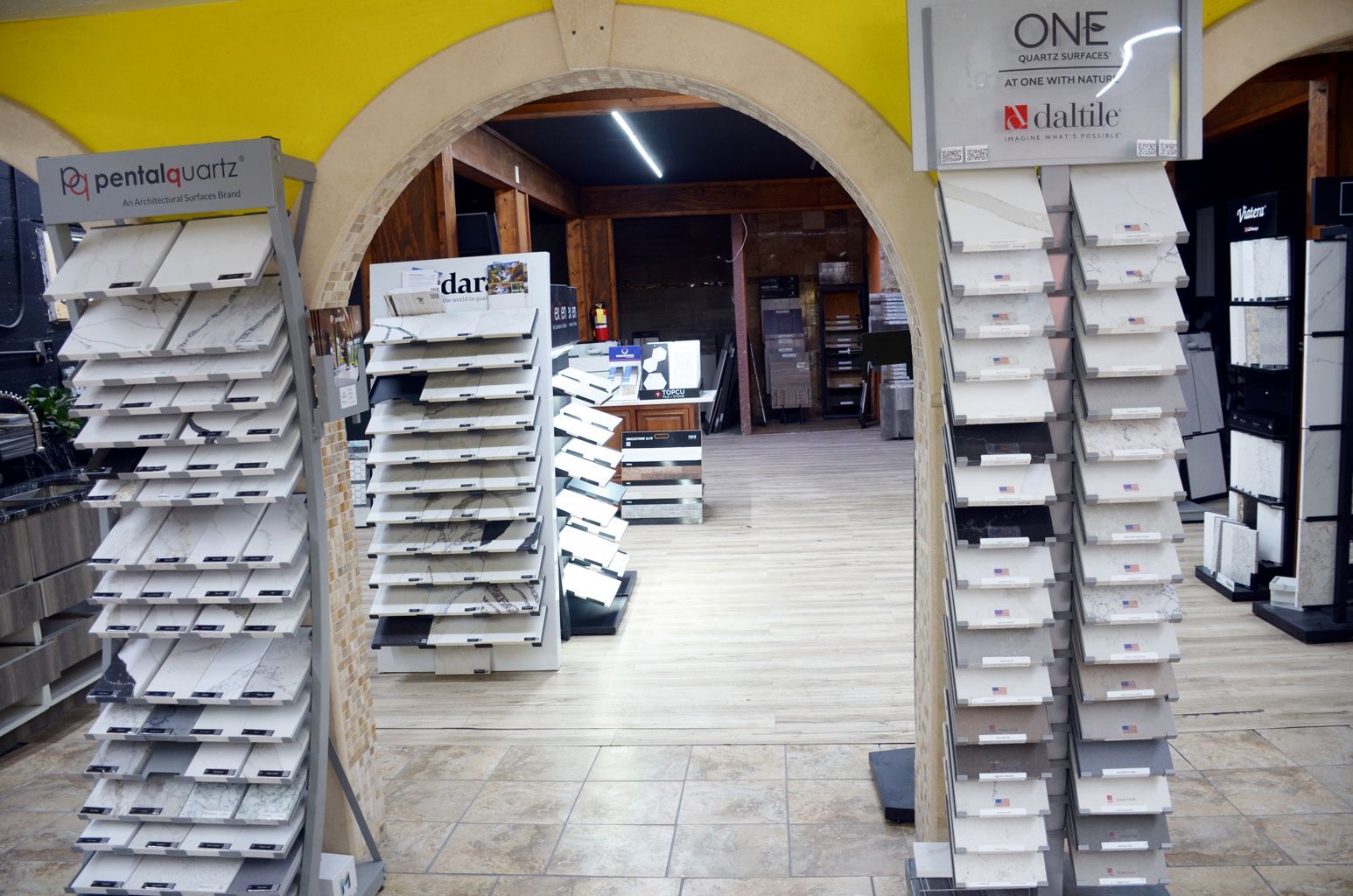 Store entrance with tall racks of white display trays under a yellow archway.