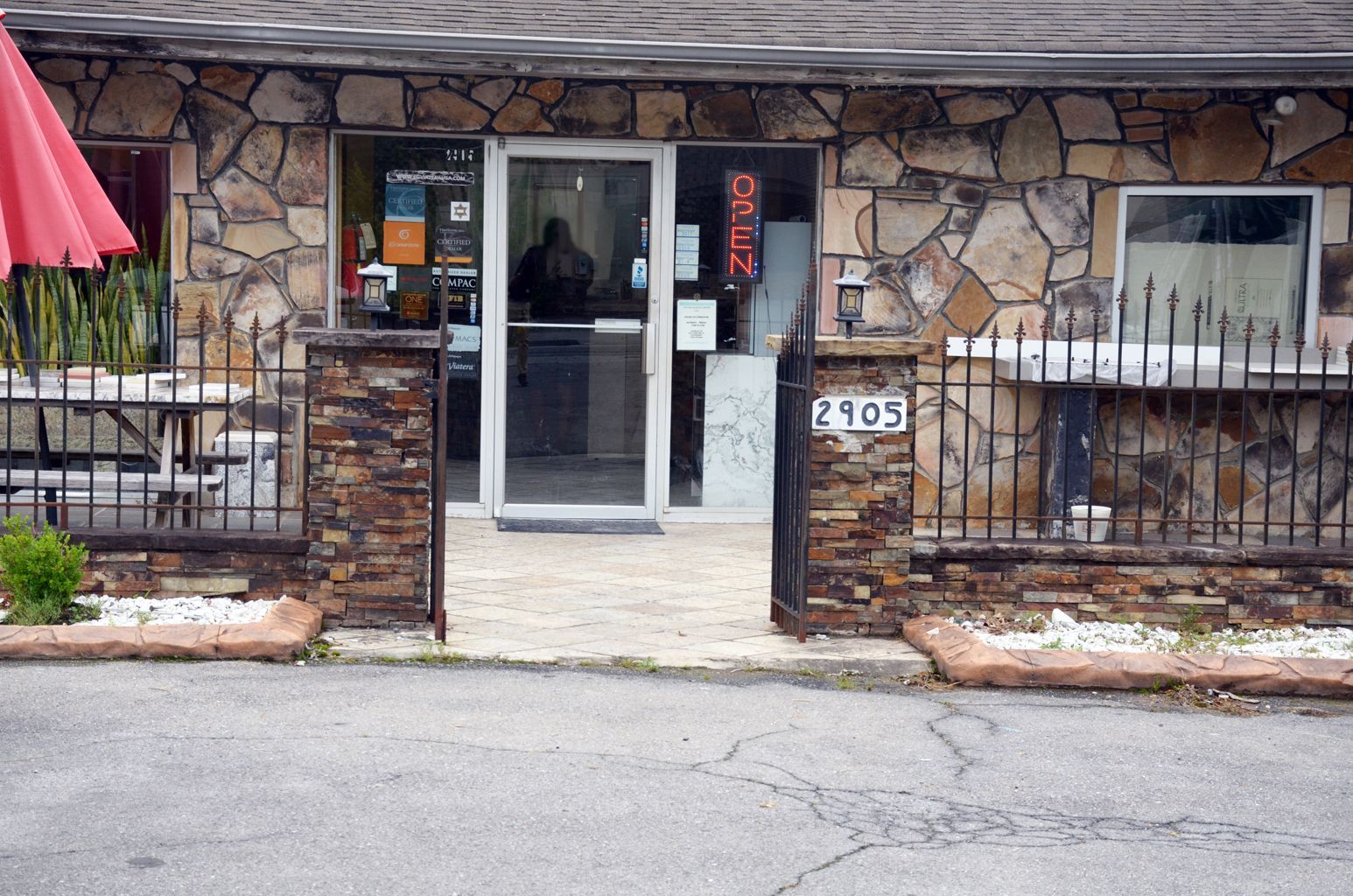 Stone storefront entrance with glass door, brick pillars, and sidewalk in front