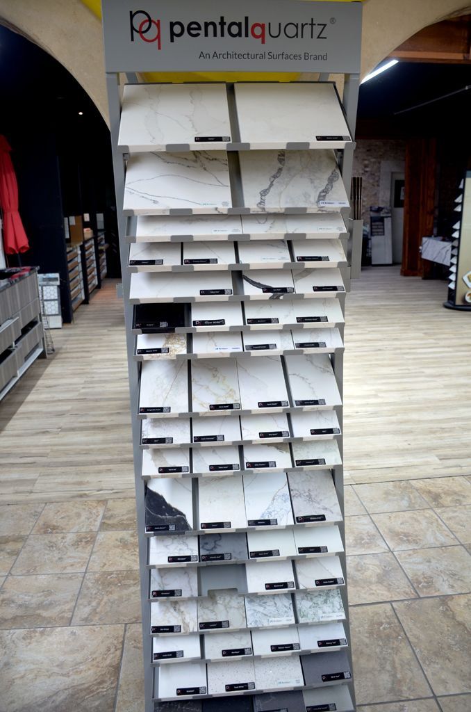 Tall white display rack with many small white envelopes or trays in a store aisle, under a Pentalquartz sign