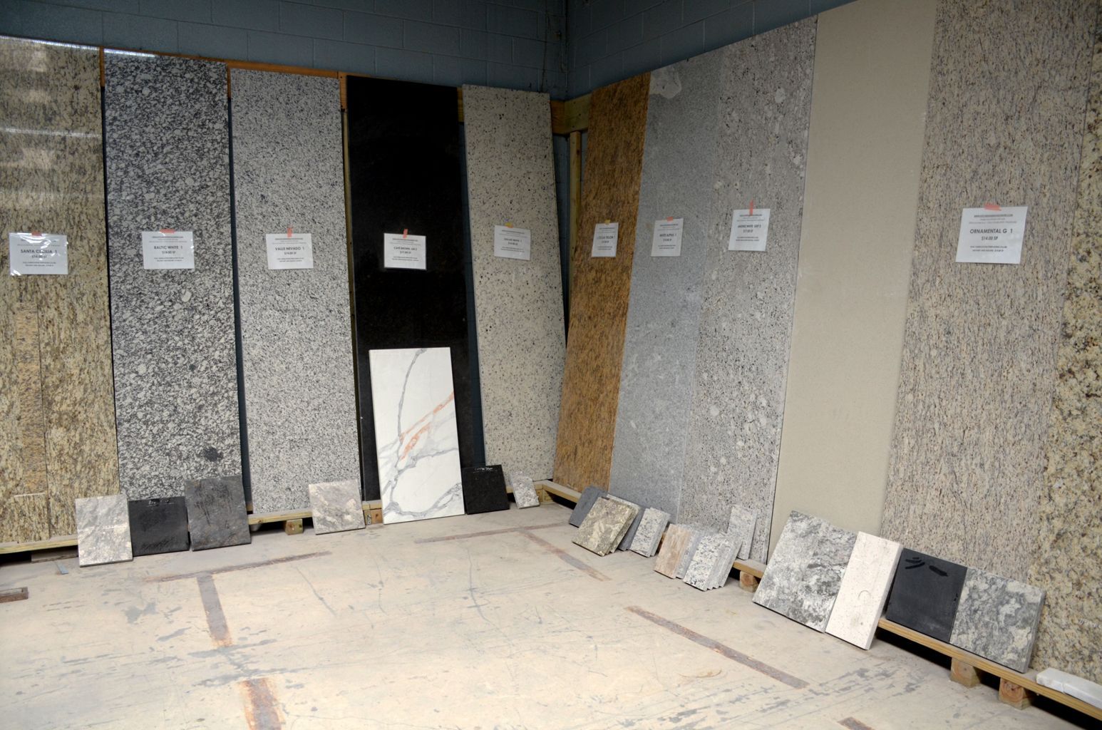 Display of stone samples leaning against walls in a showroom or warehouse corner