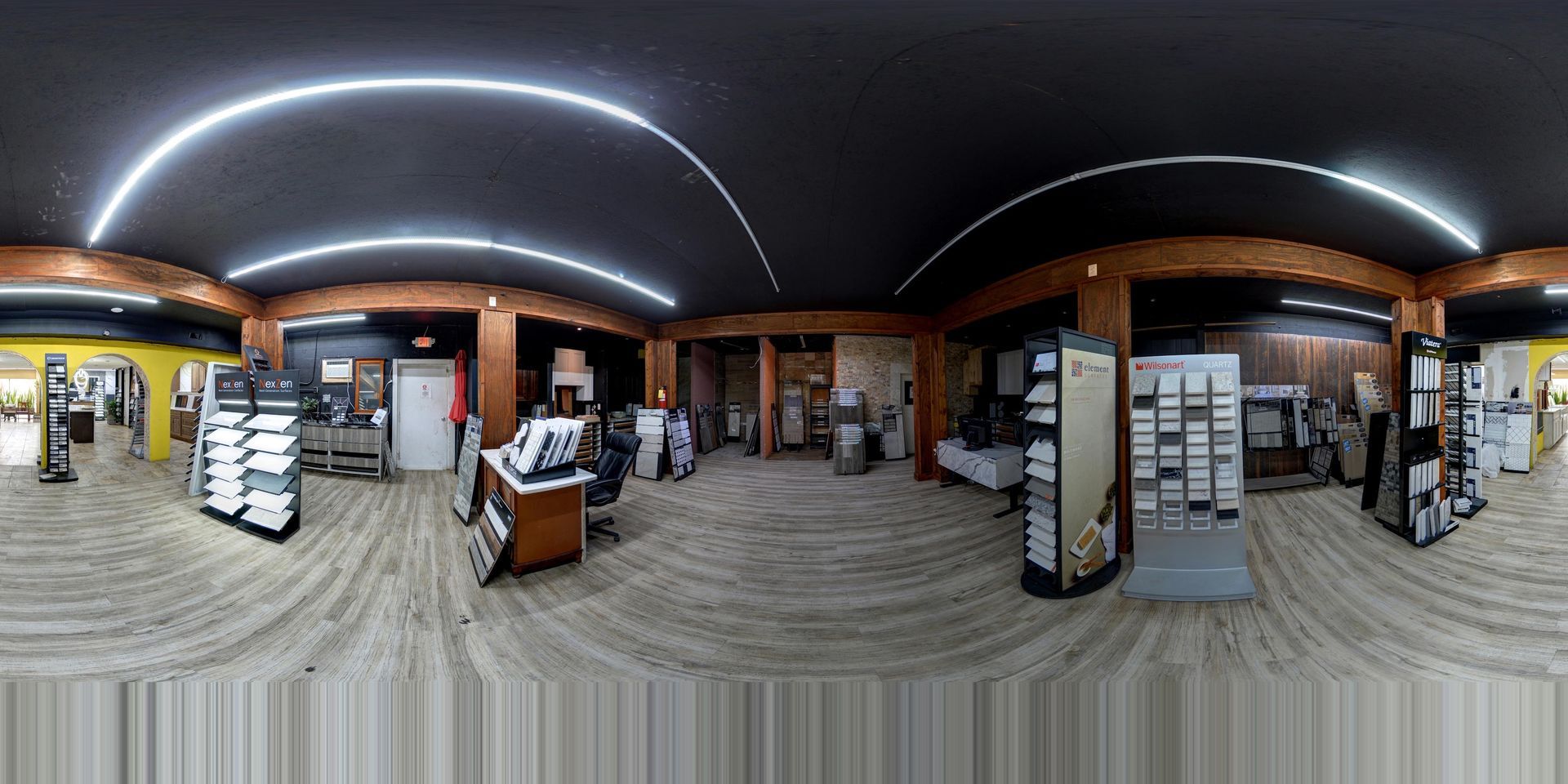 Wide-angle view of a store interior with aisles, shelves, and a central counter under curved ceiling lights