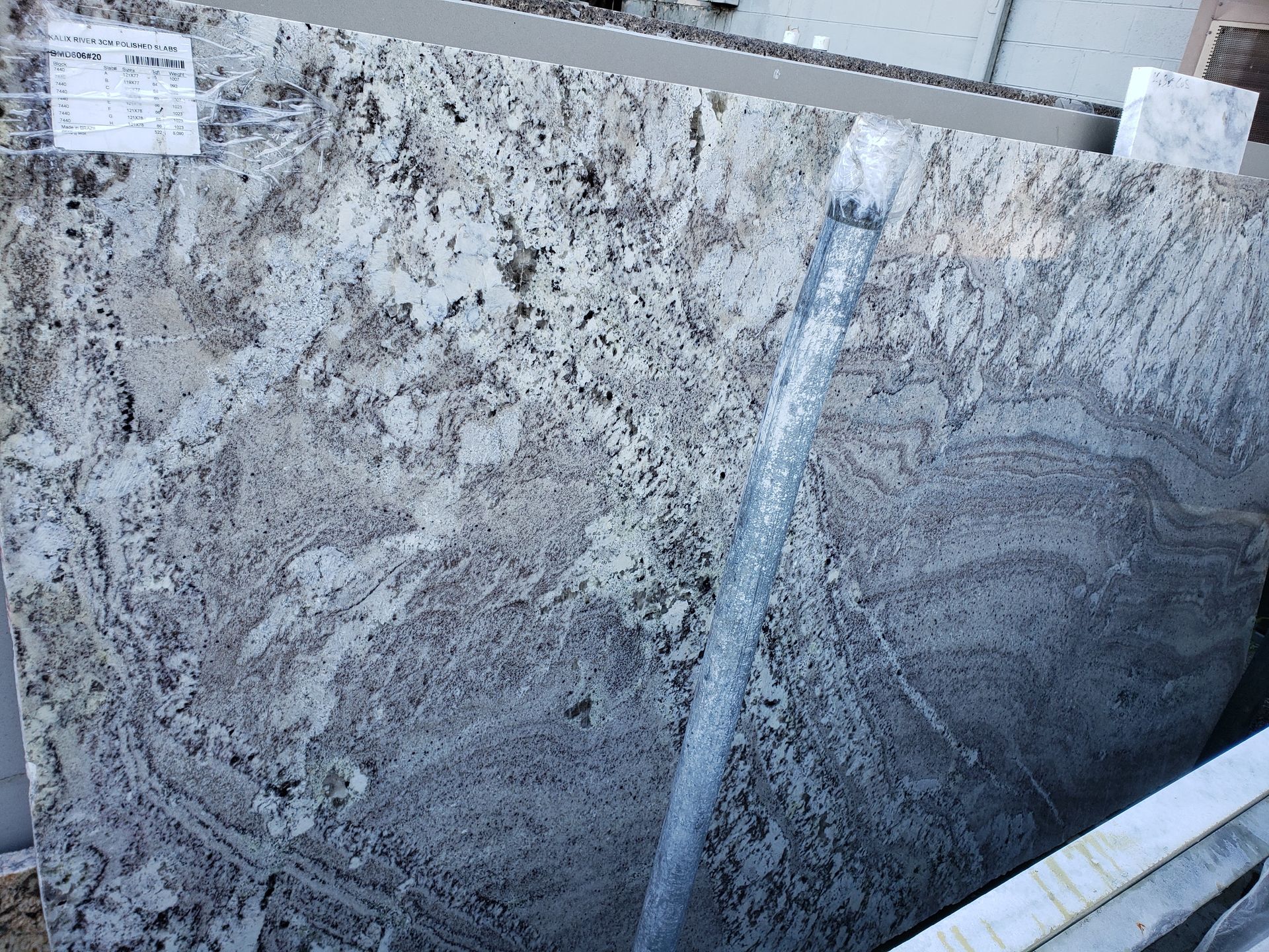 Stacked gray granite slabs with white and black veining in a warehouse setting