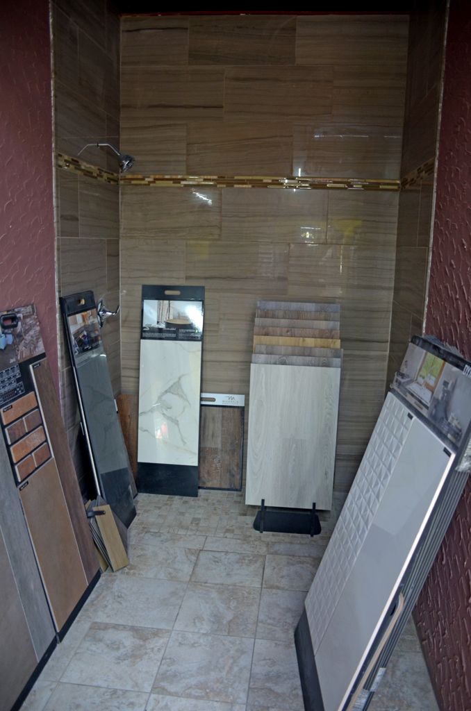 Narrow storage alcove with leaning boards and stacked panels against wooden walls and a tiled floor