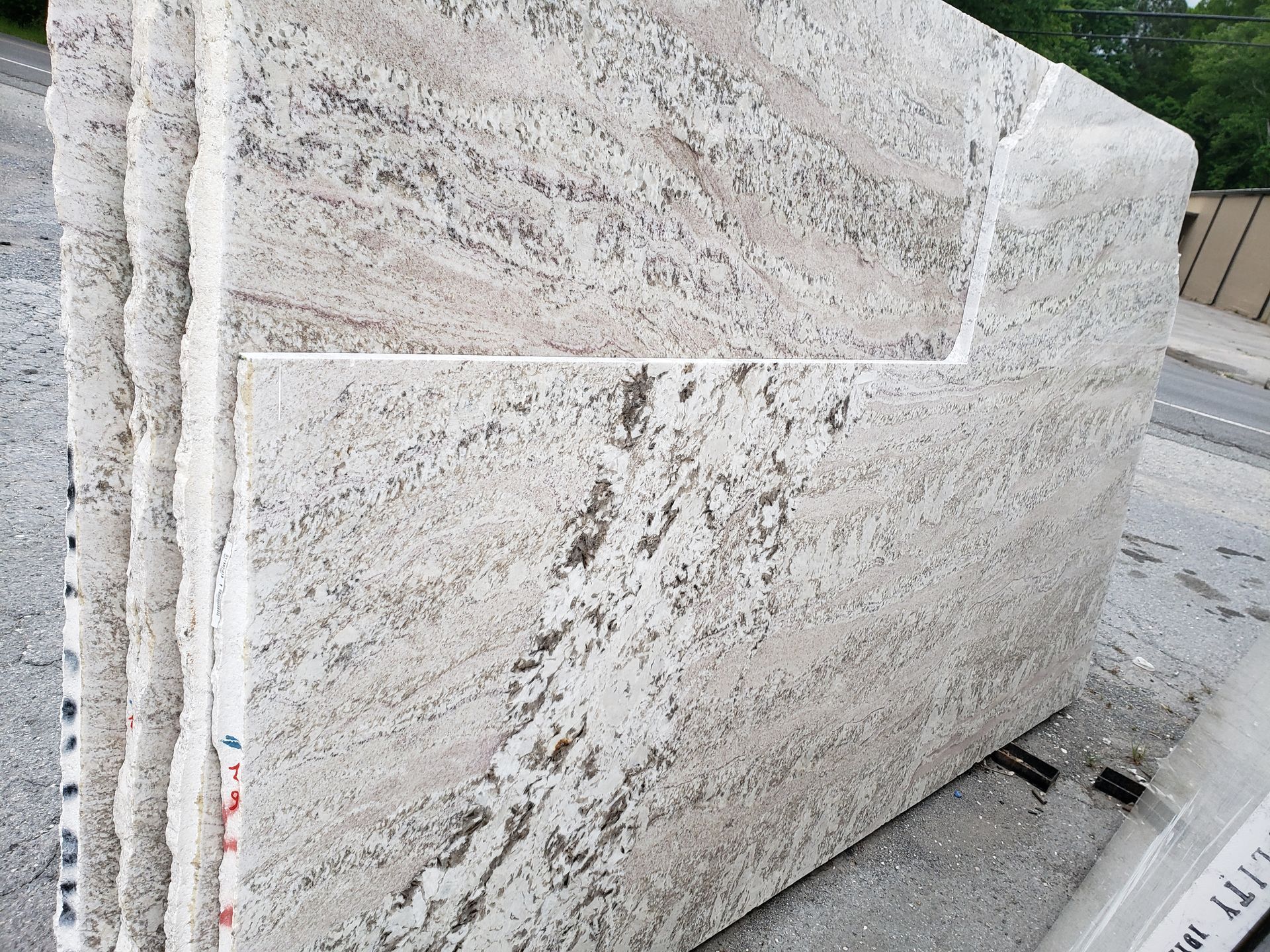 Light gray stone wall with rectangular panels along a sidewalk.