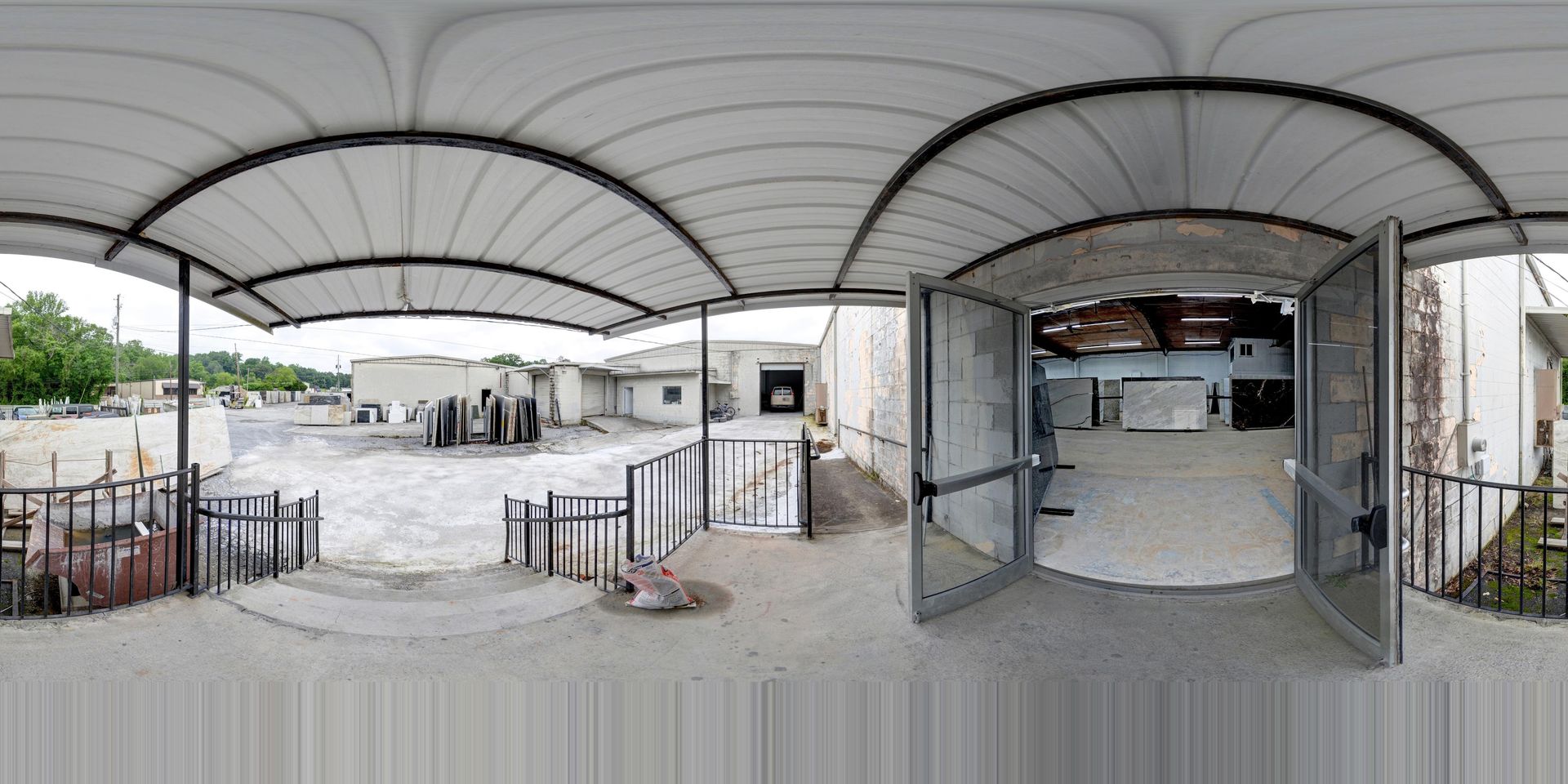 Covered outdoor walkway leading to a white courtyard building entrance with railings and stairs