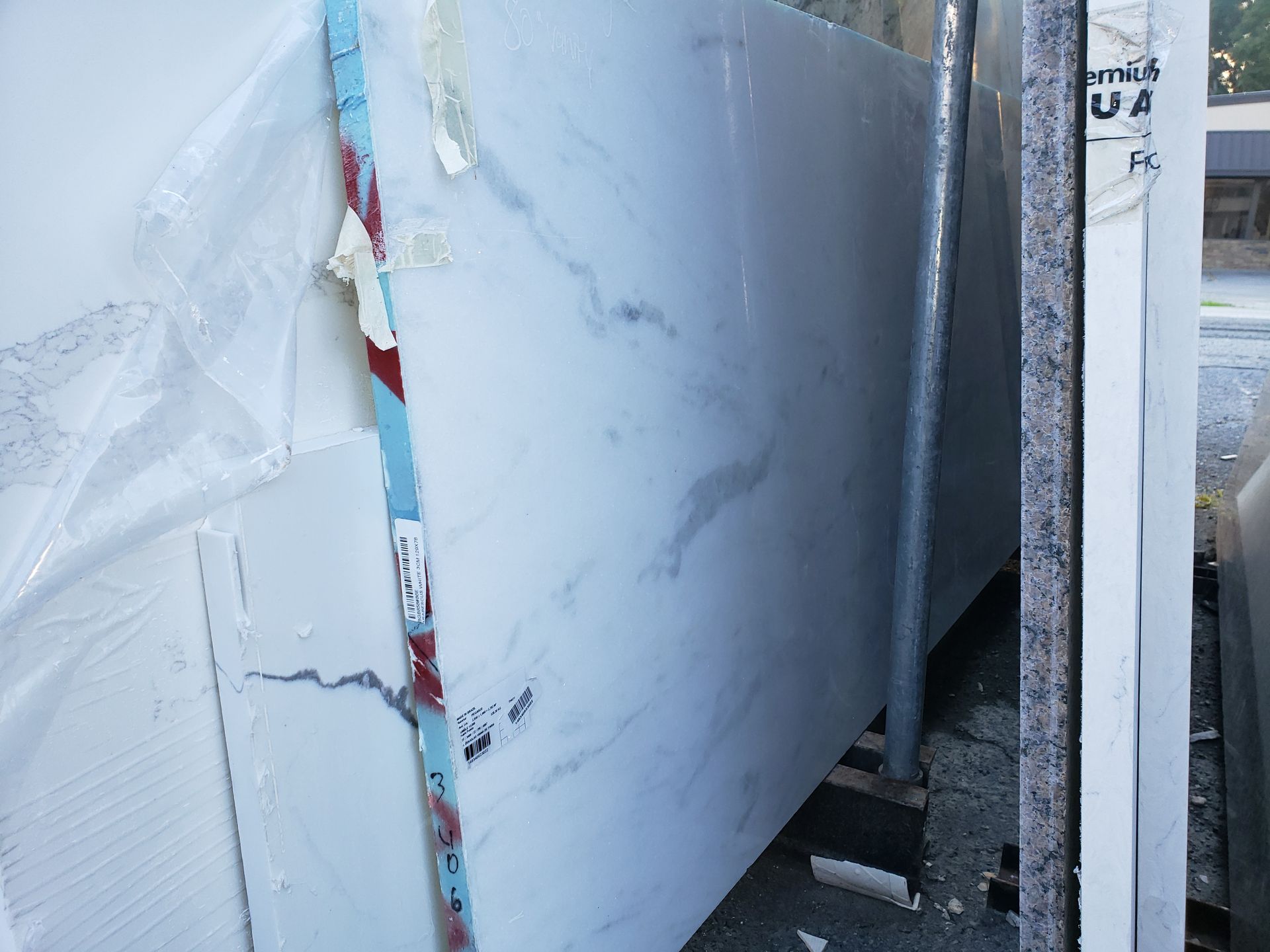 Broken white wall panel with exposed red insulation in a construction area