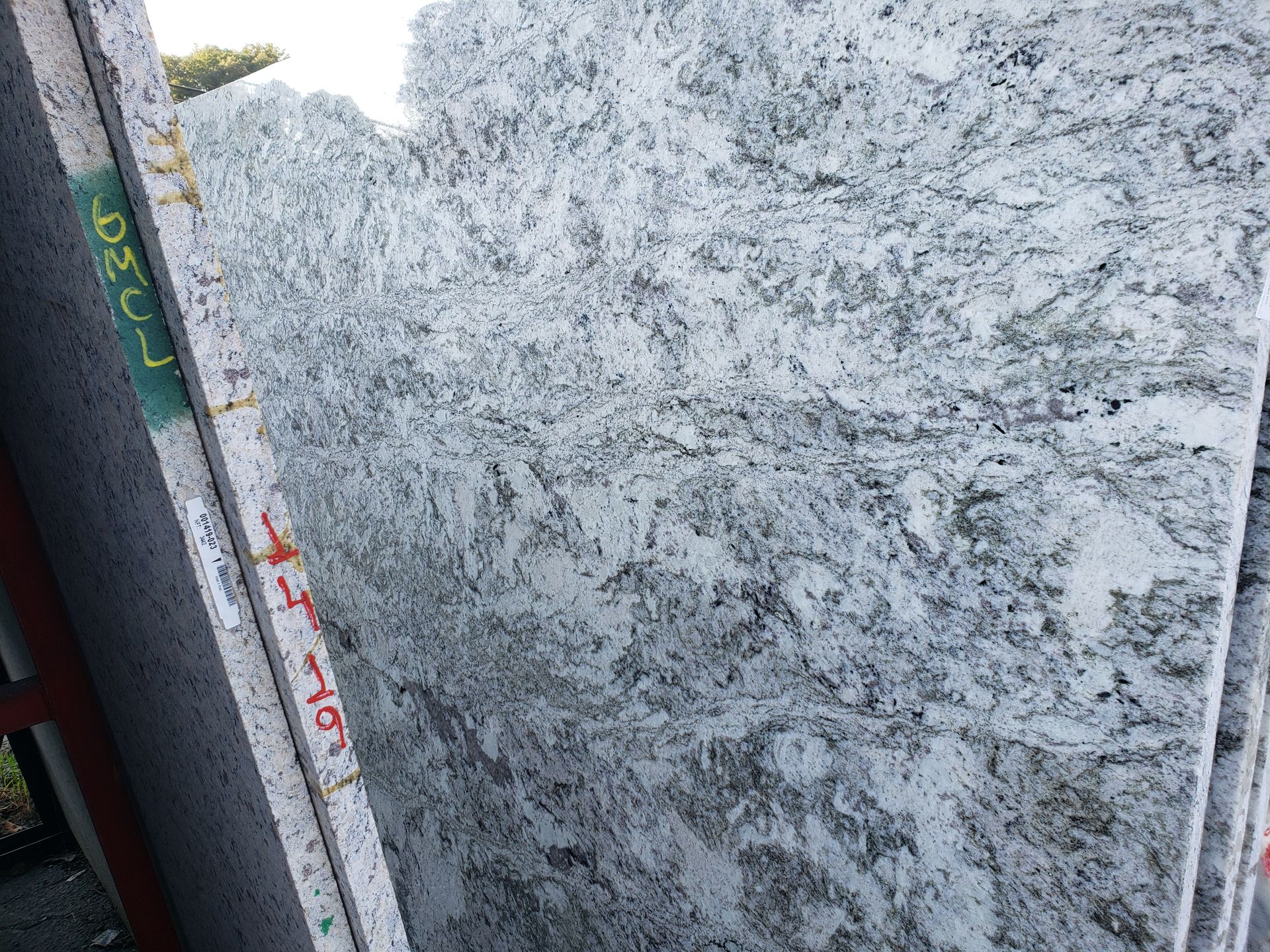 Stacked granite slabs with gray-and-white speckled surfaces and visible edge markings.