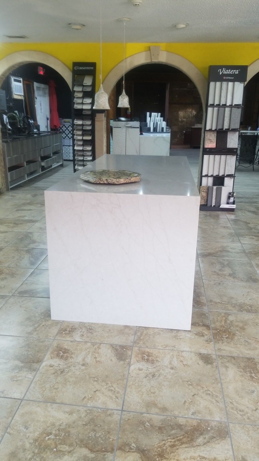 Empty salon lobby with a white reception counter, mirrors, product shelves, and arched doorways.