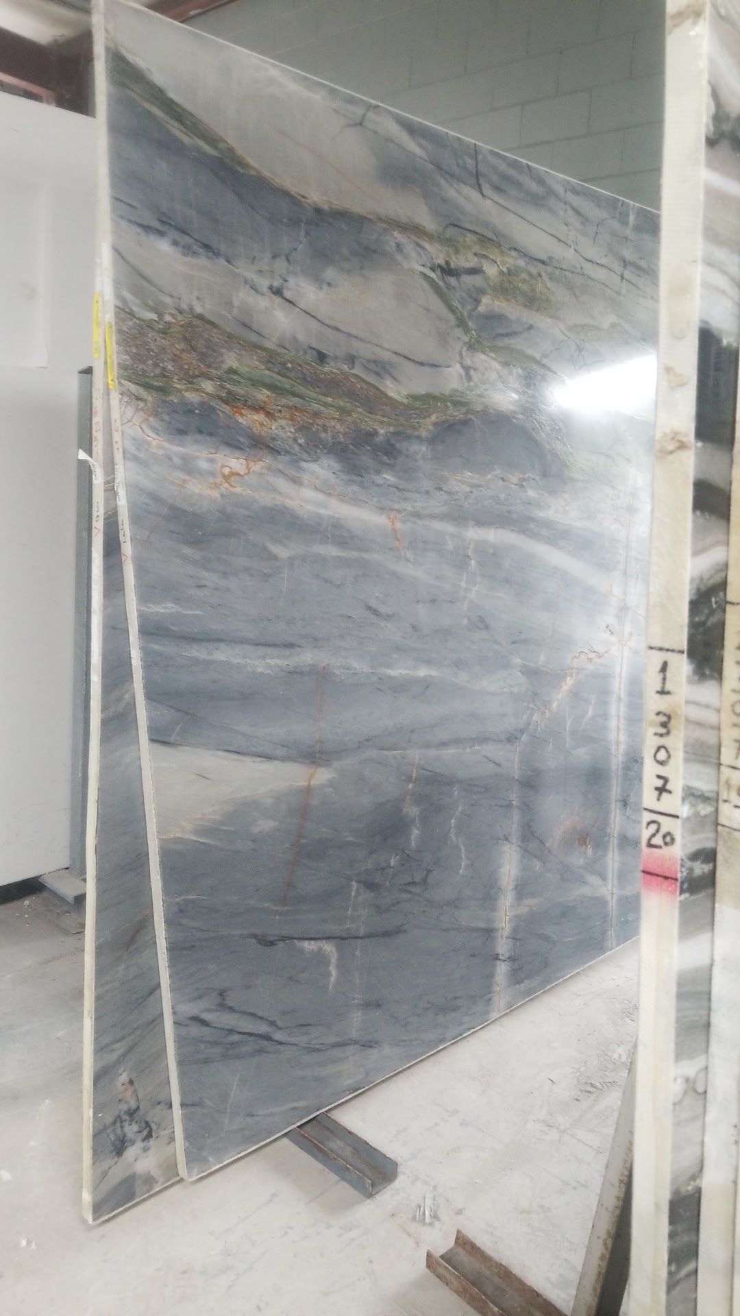 Large reflective gray panel leaning against a wall in an unfinished room.