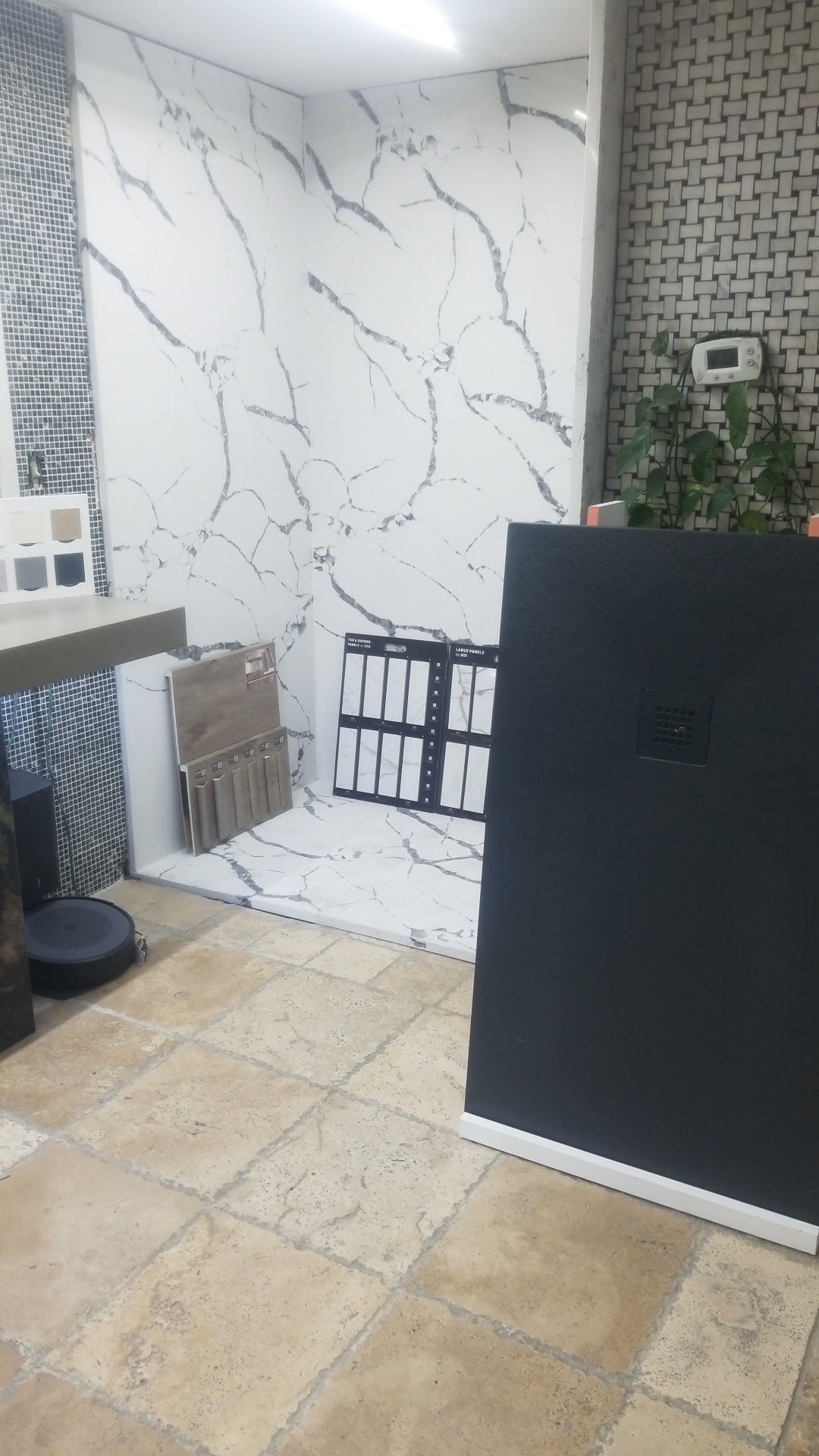 Small room with marble-pattern wall, beige tile floor, black cabinet, and stacked materials near a window.