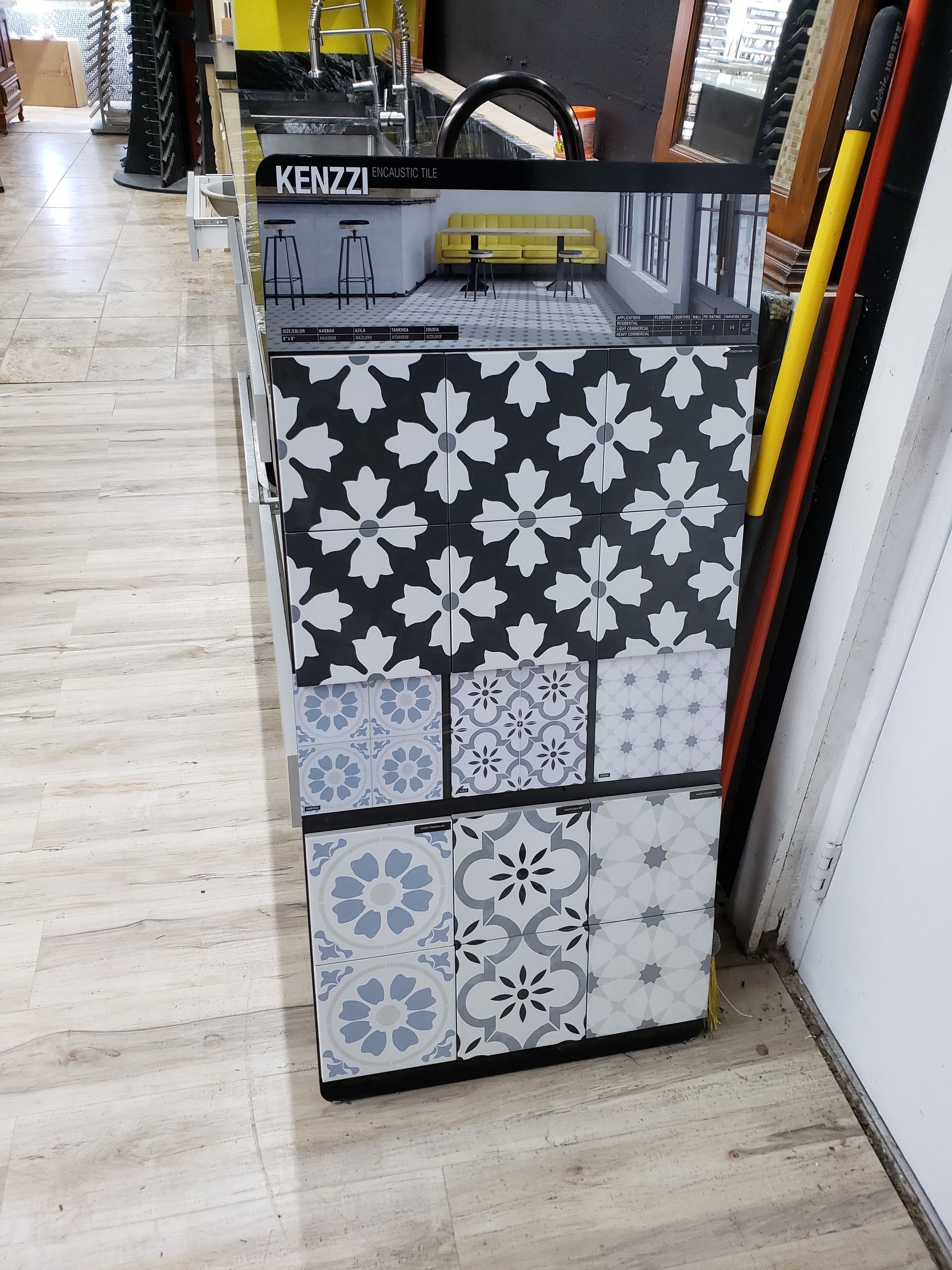 Patterned tile display rack in a store aisle with black, gray, and blue decorative tiles