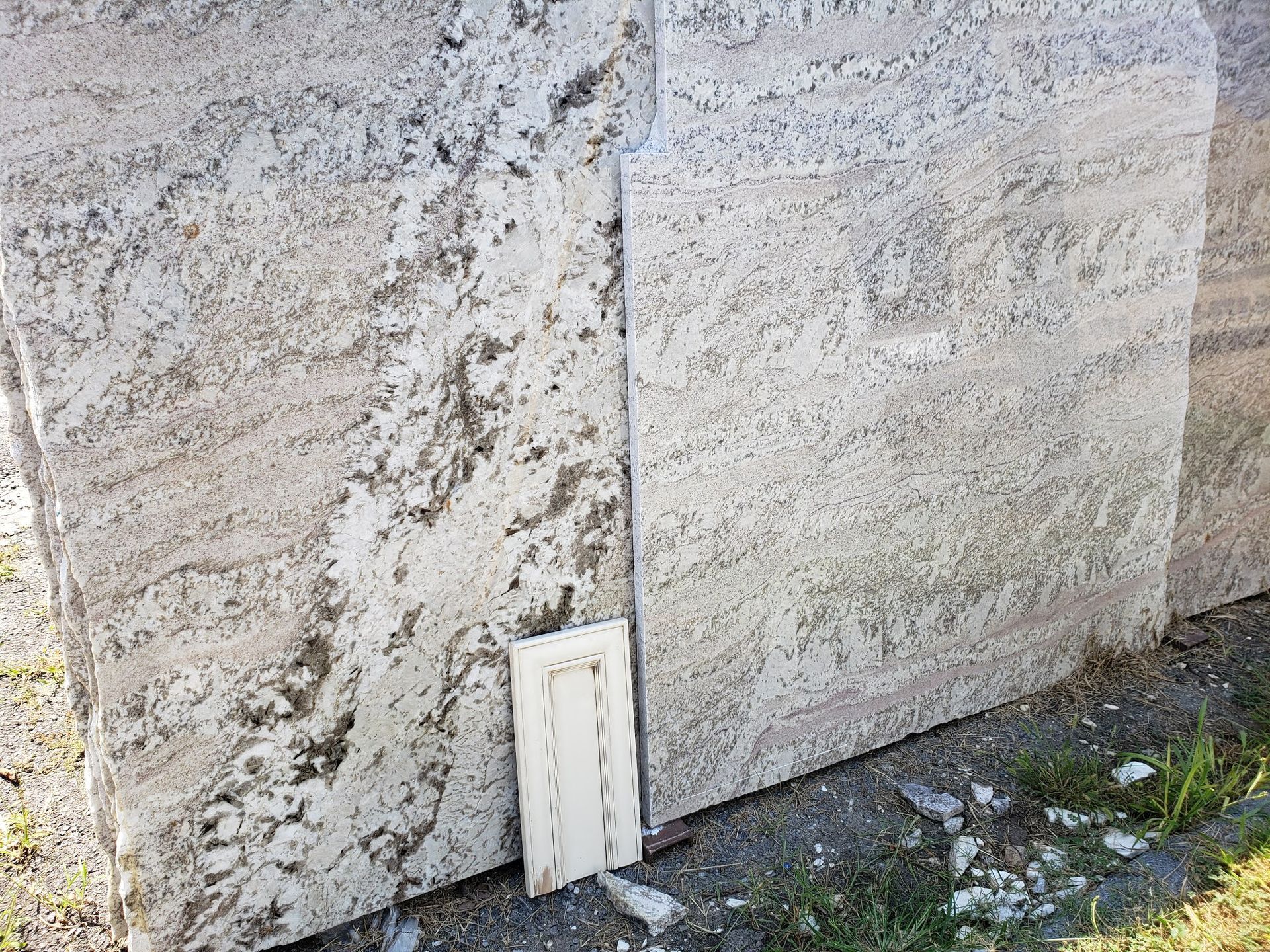 Weathered stone wall with a small white panel leaning at the base on a mossy ground.